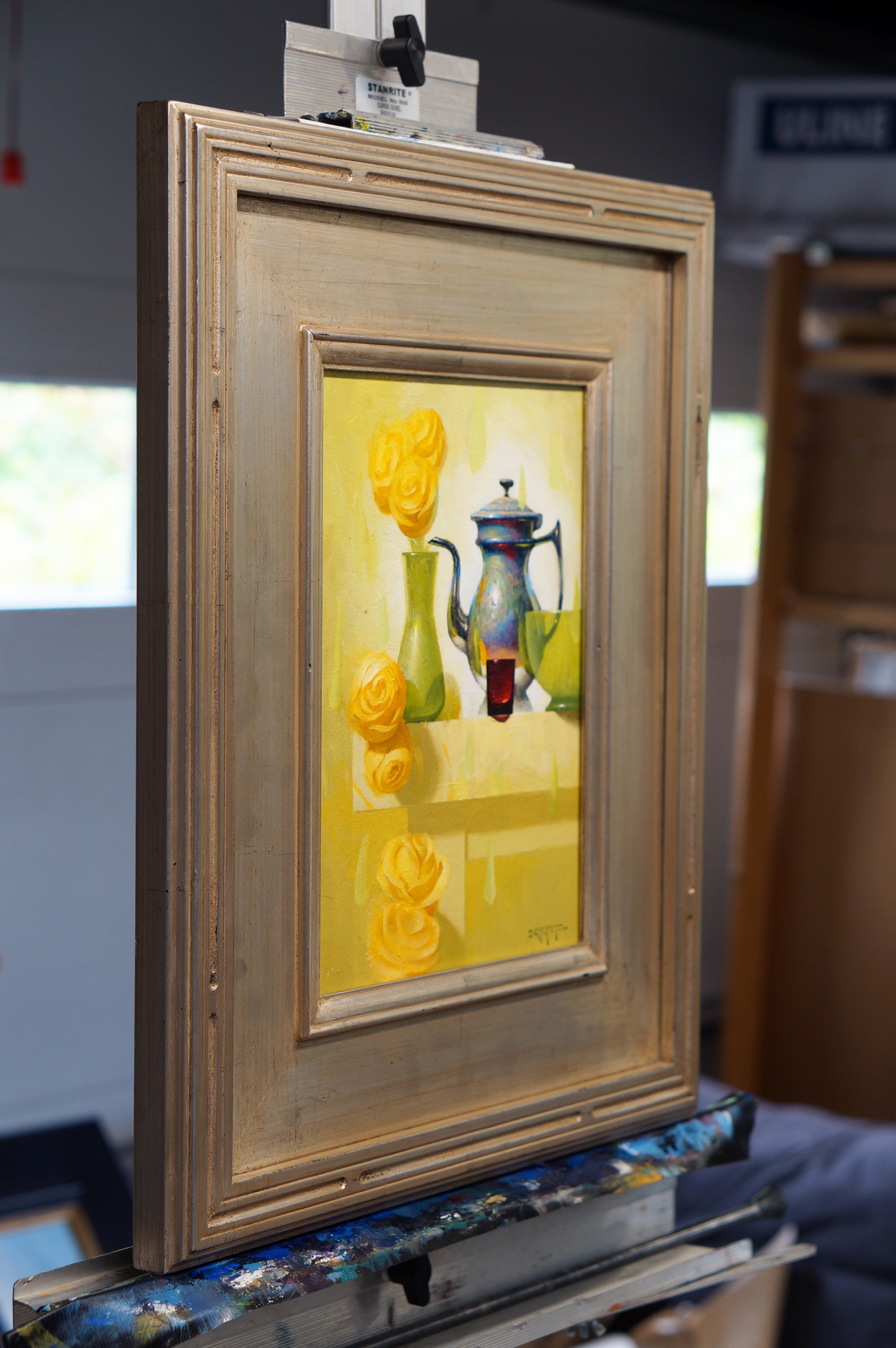 A still life painting featuring a metallic teapot, green vase with yellow roses, and abstract shapes on a light background.