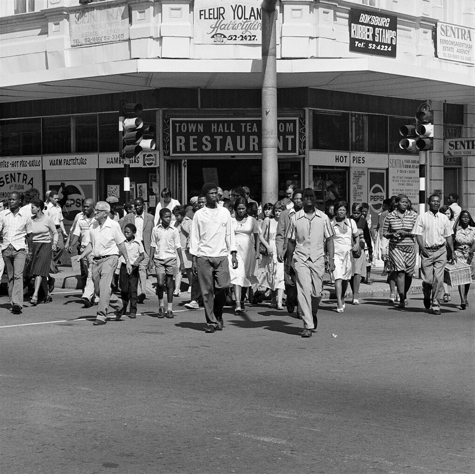 A group of people walking down a street in front of a building.