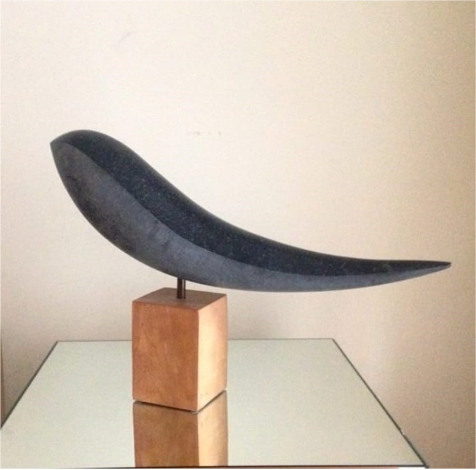 A sculpture of a crescent shaped object on a wooden block.