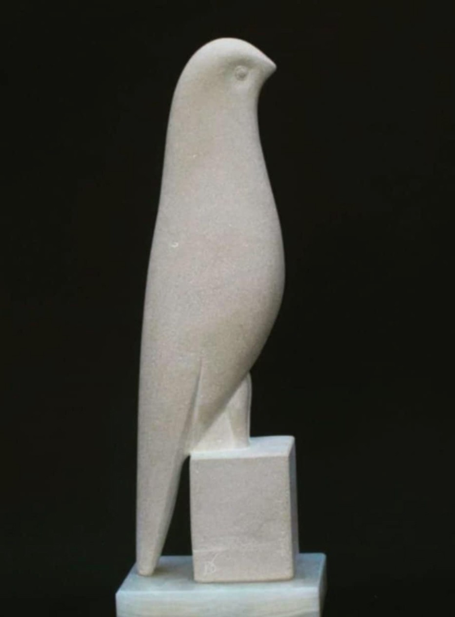 A white bird sitting on top of a marble block.