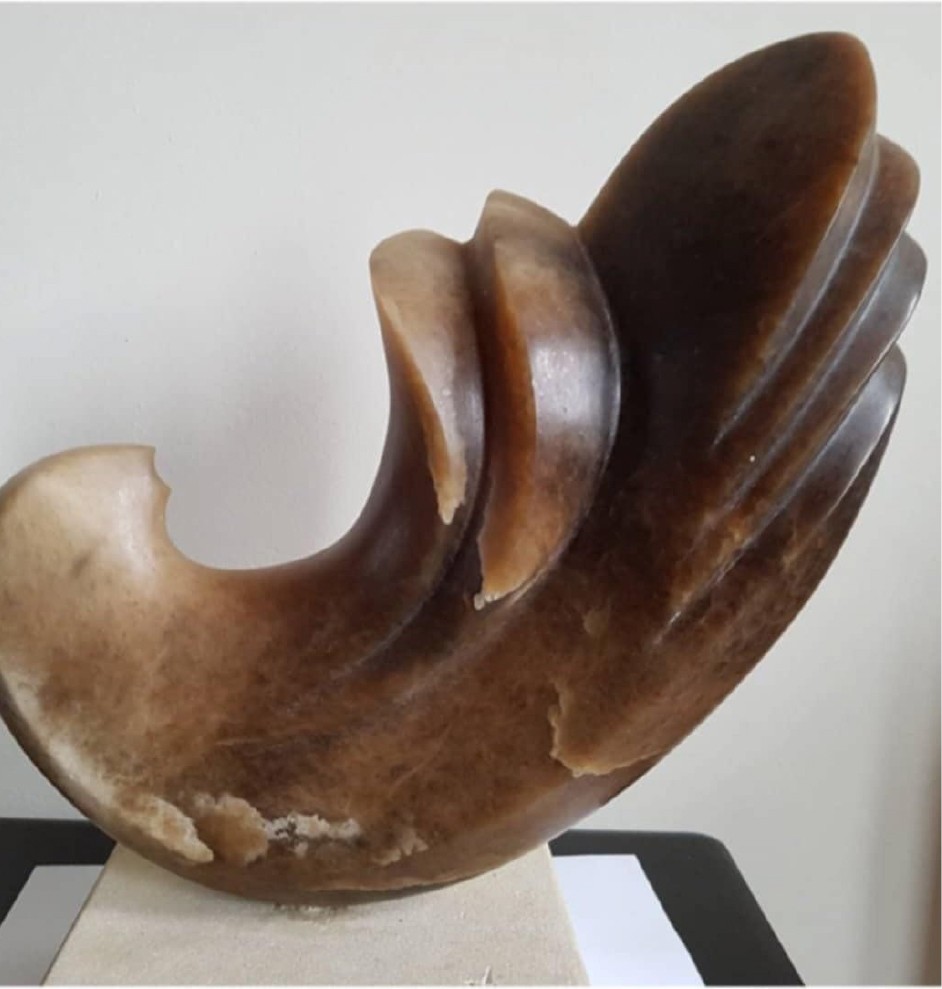 A sculpture of a large horn on a white pedestal.