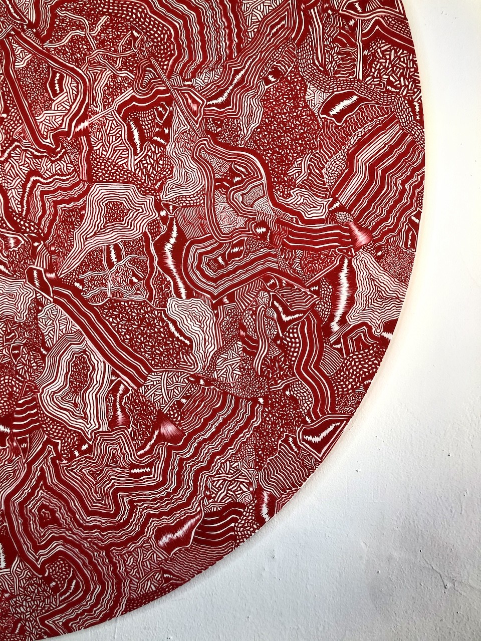A man is painting a large red circle on a wall.