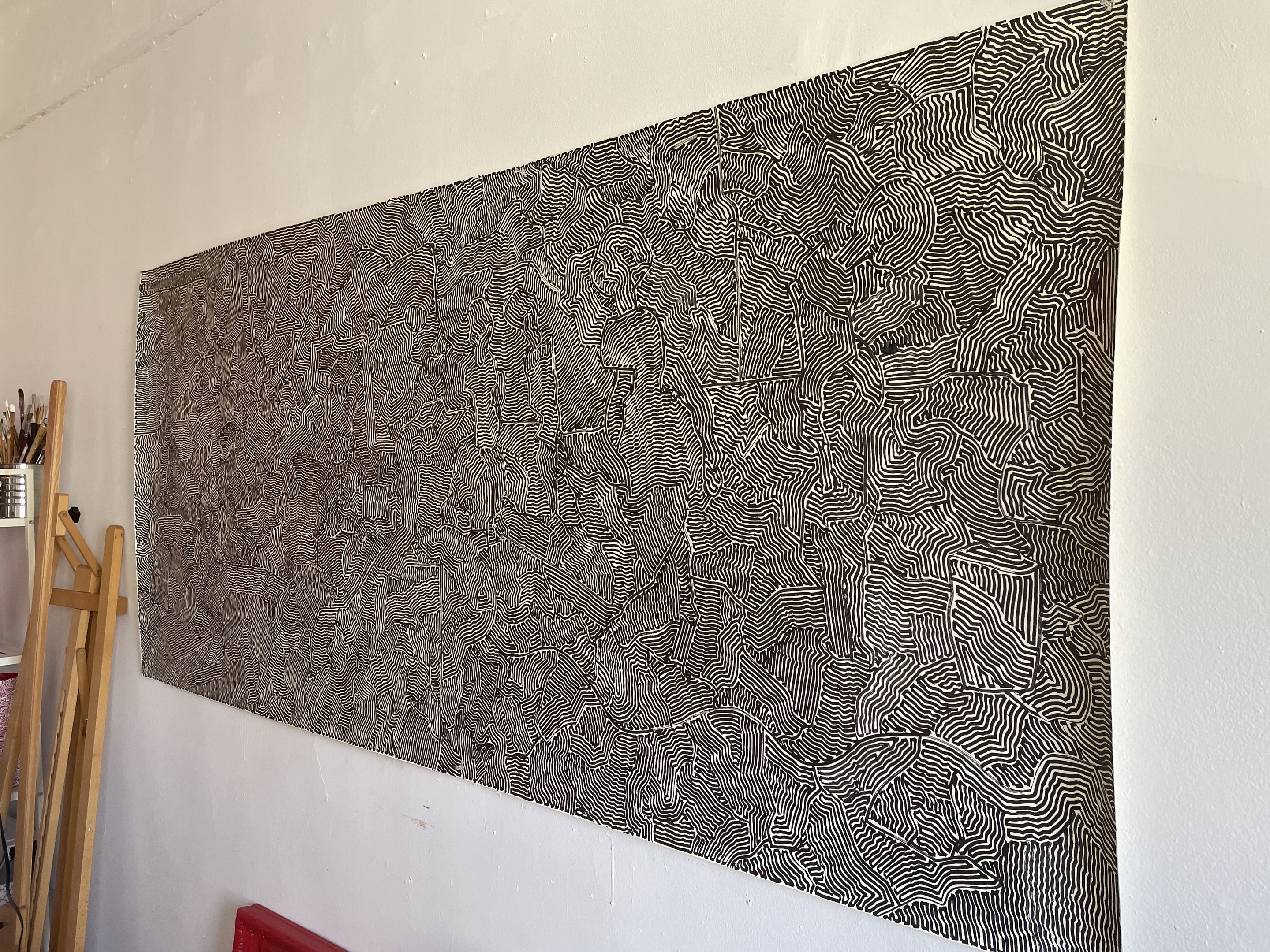 A black and white painting hanging on a wall next to a chair.