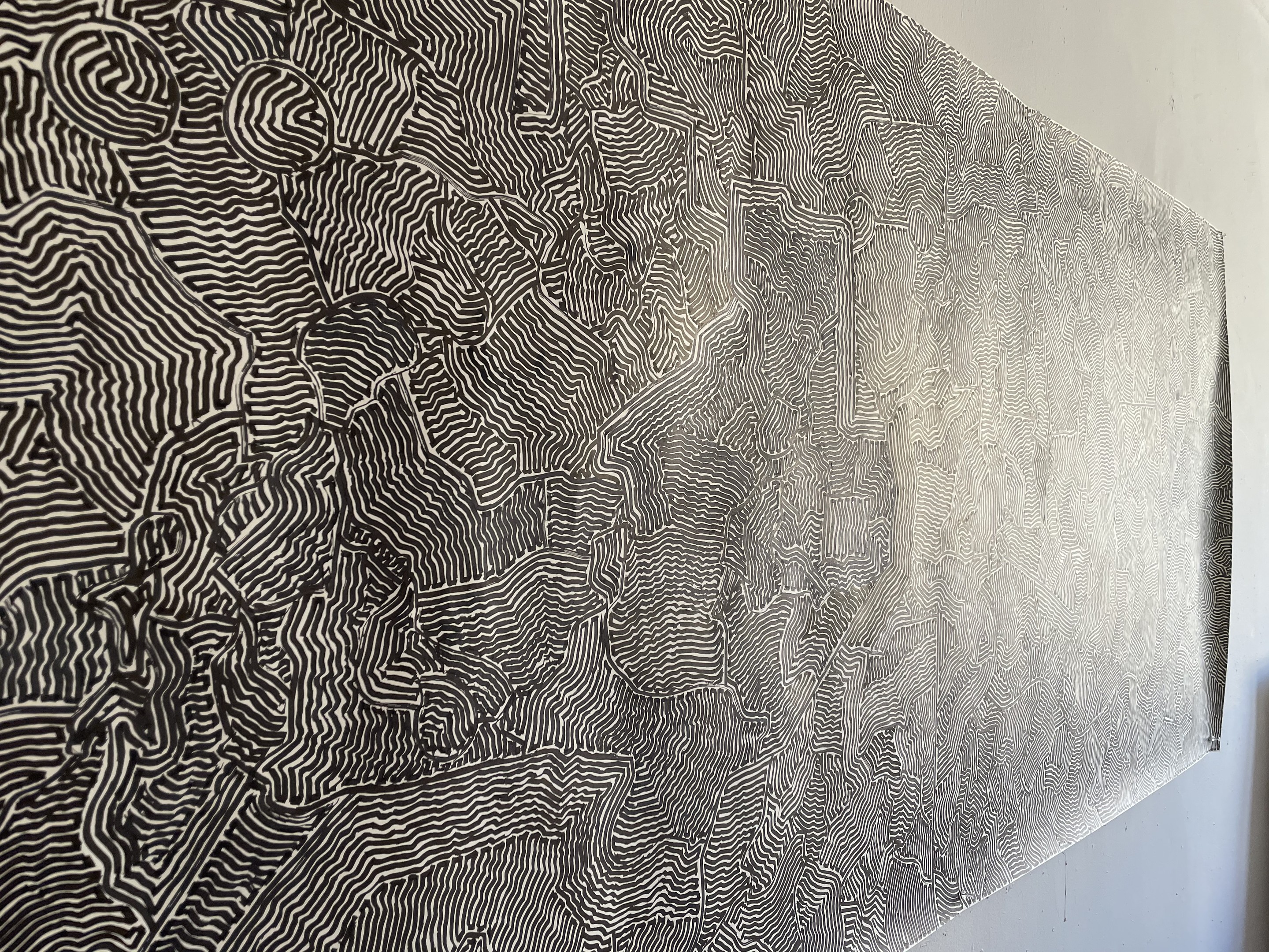 A black and white painting hanging on a wall next to a chair.