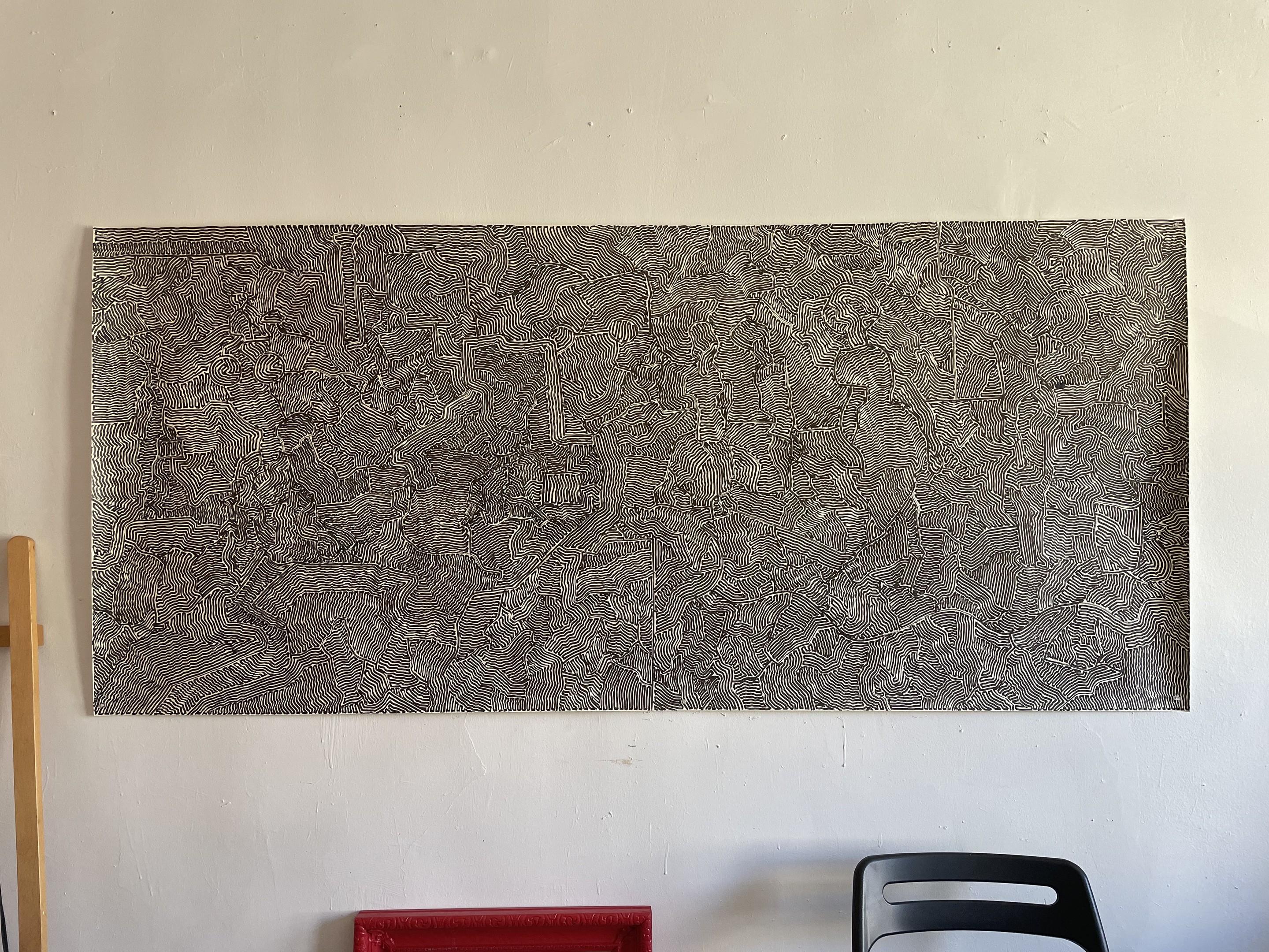 A black and white painting hanging on a wall next to a chair.