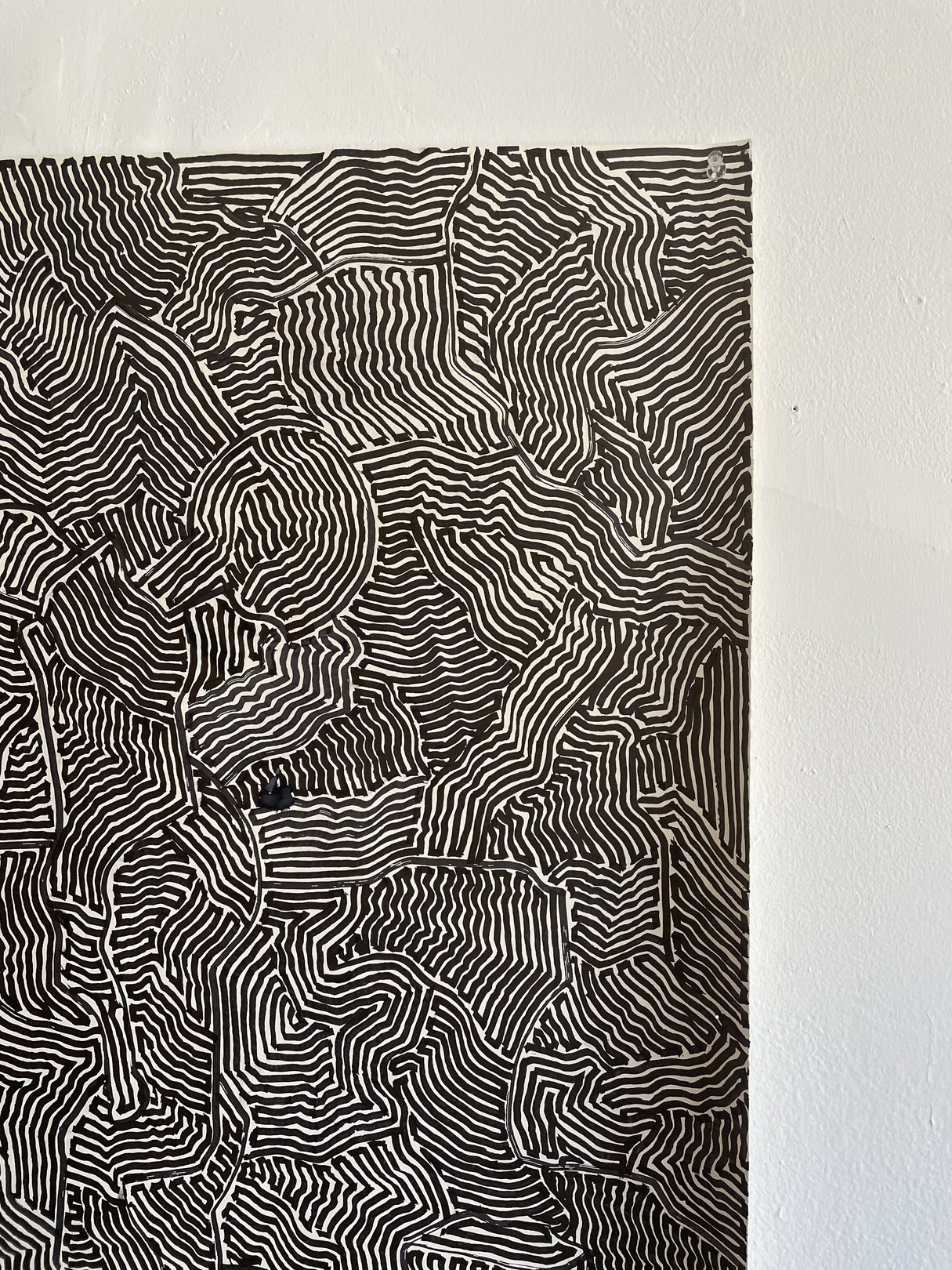 A black and white painting hanging on a wall next to a chair.