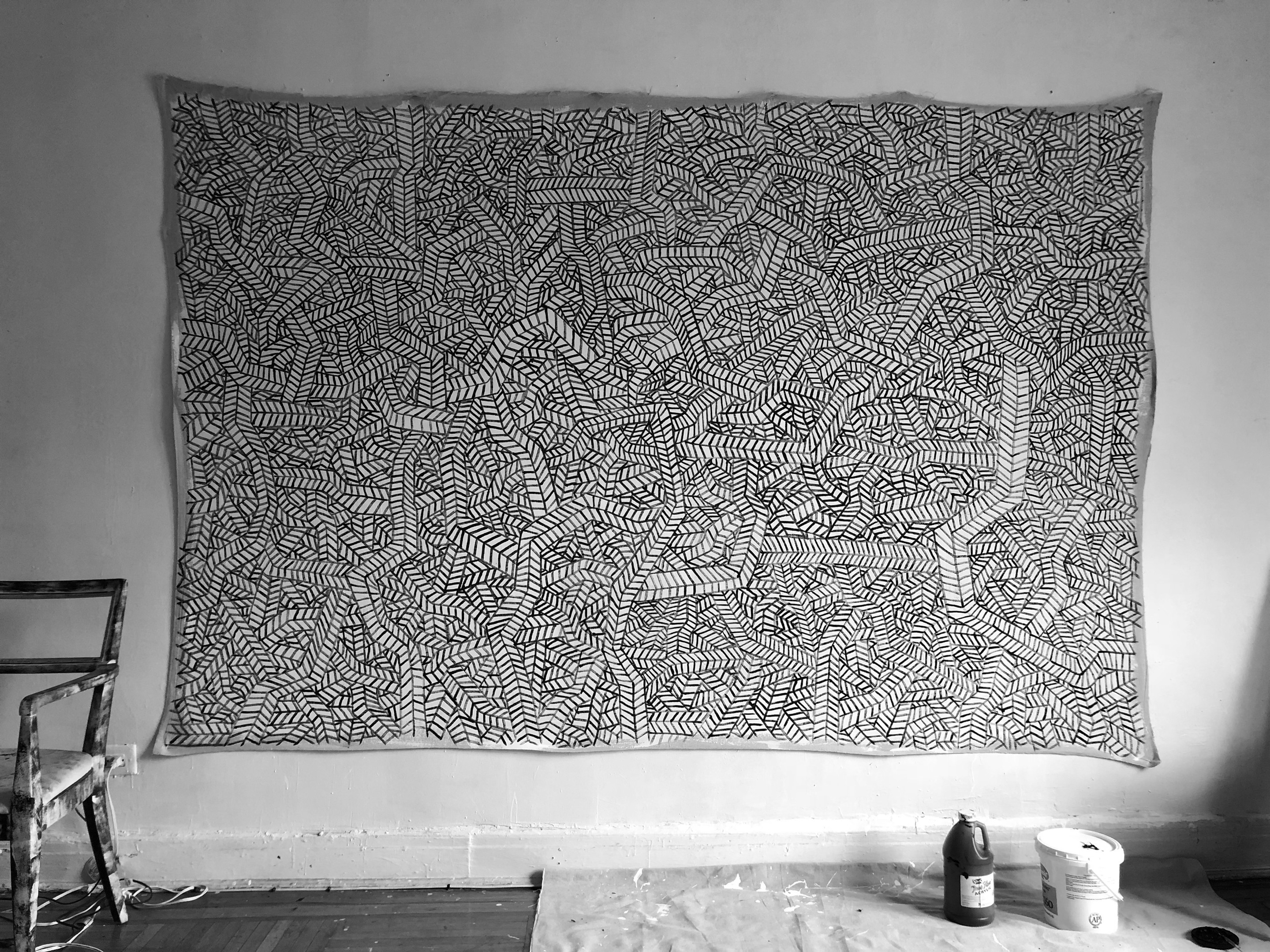 A black and white photo of a large piece of art hanging on a wall.