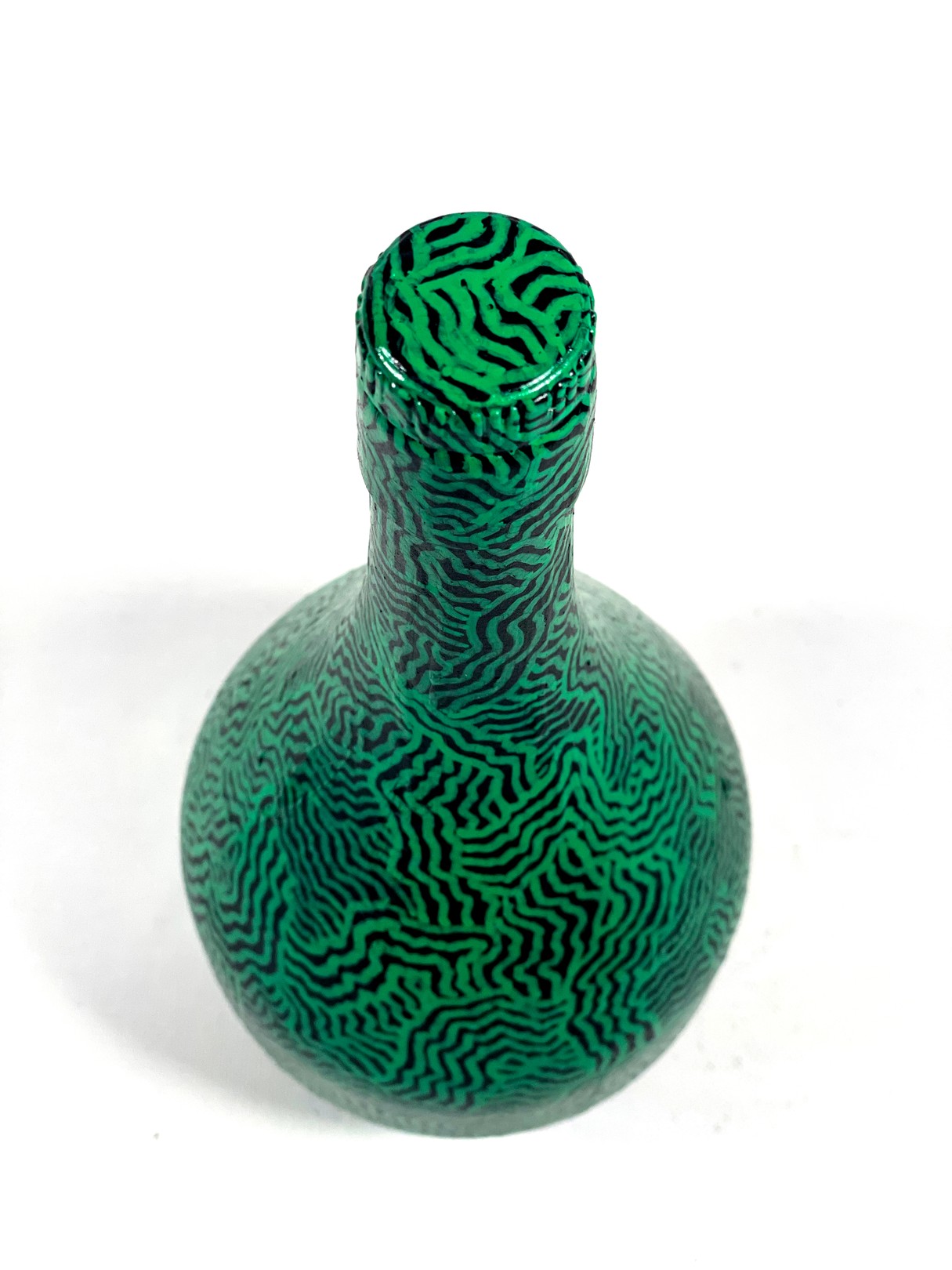 A green vase with a pattern on it sitting on a white surface.