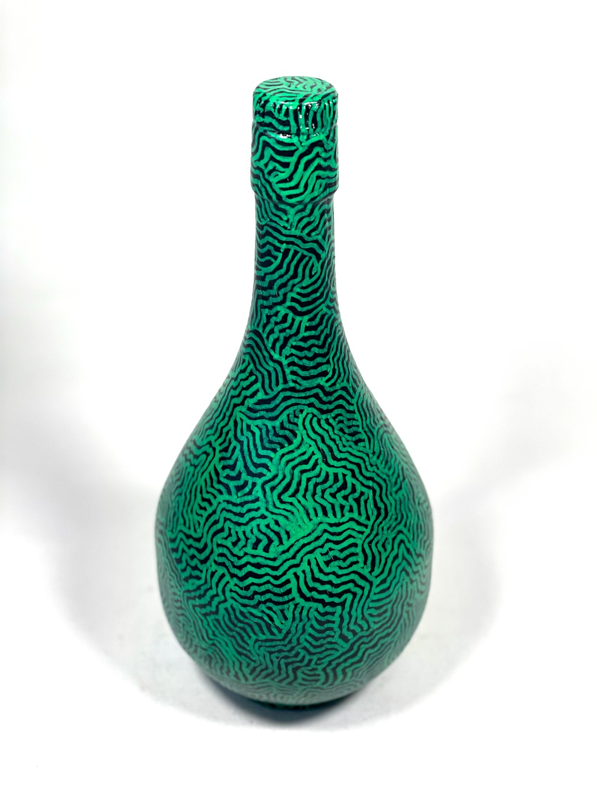 A green vase with a pattern on it sitting on a white surface.
