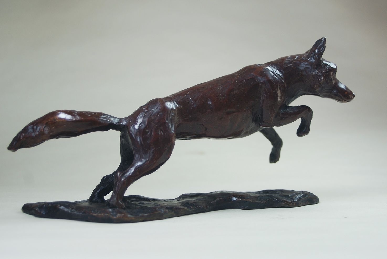 A bronze sculpture of a running fox on a rock.