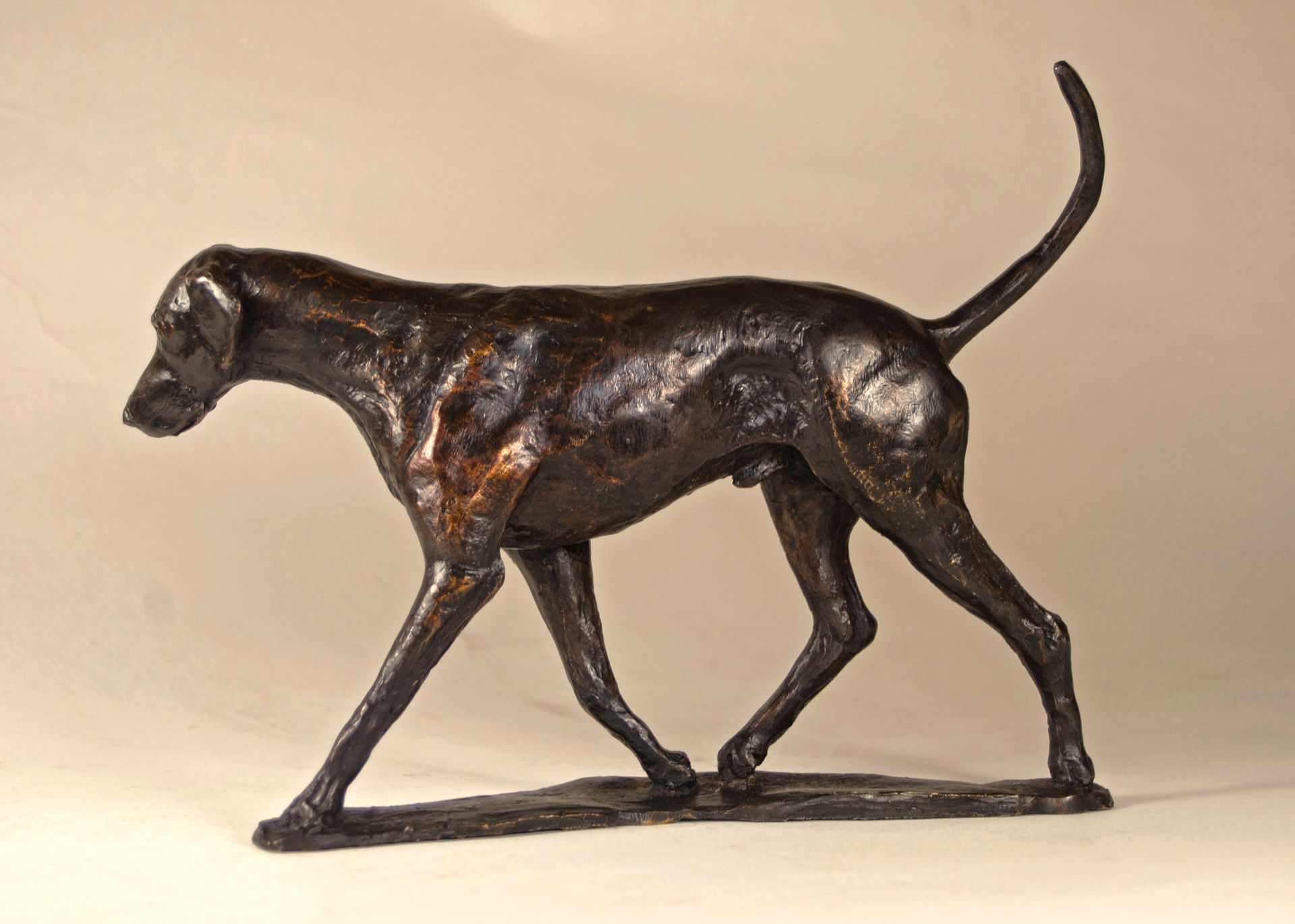 A bronze sculpture of a dog on a white background.