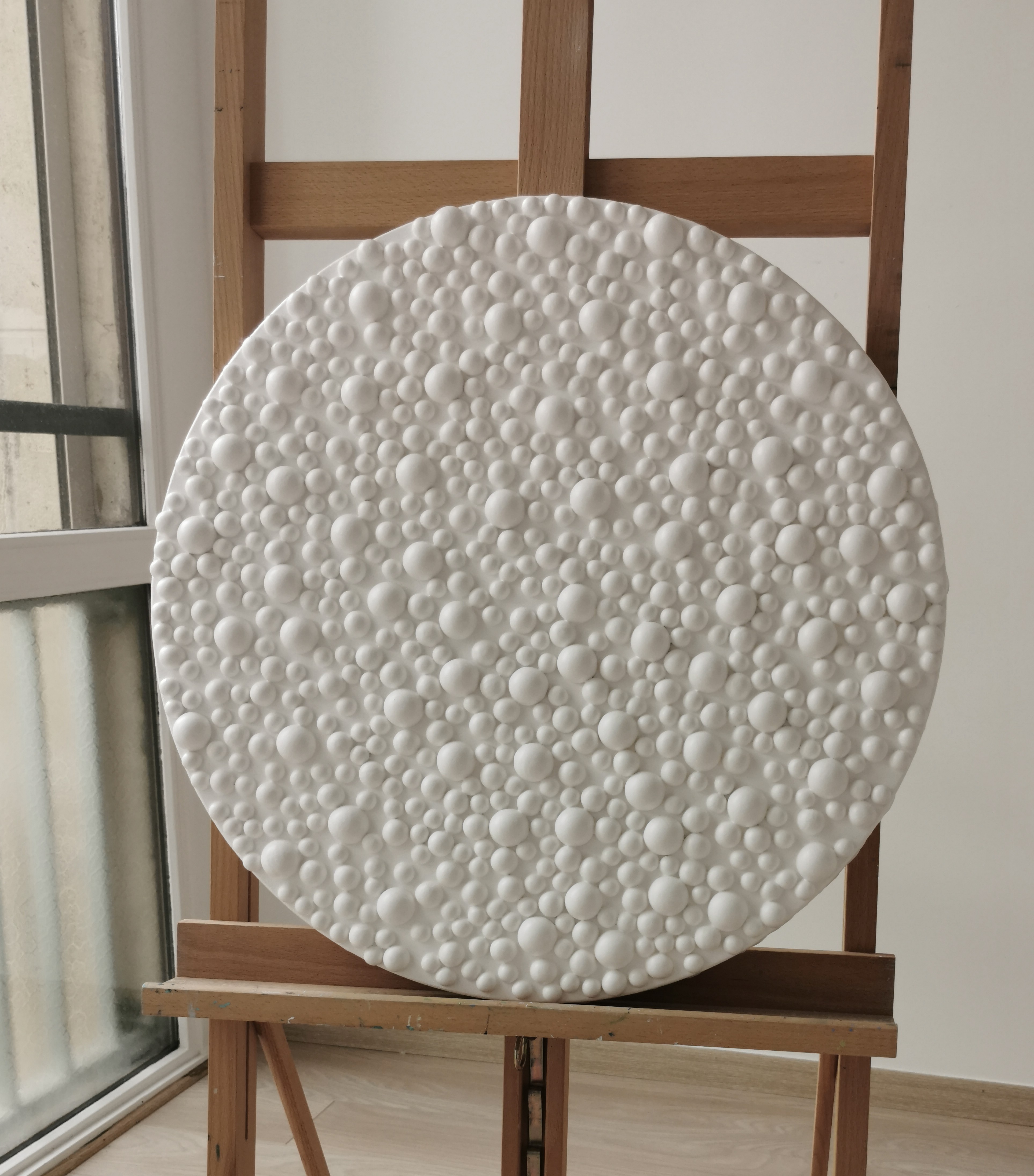 A large white plate sitting on top of a wooden easel.