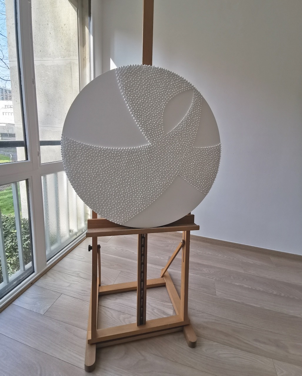 A large white sculpture on a wooden floor next to a white wall.
