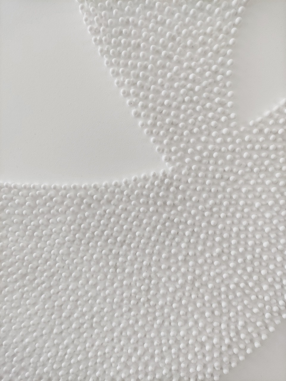 A large white sculpture on a wooden floor next to a white wall.