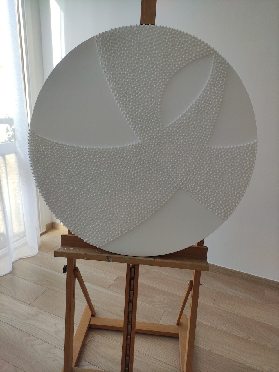 A large white sculpture on a wooden floor next to a white wall.