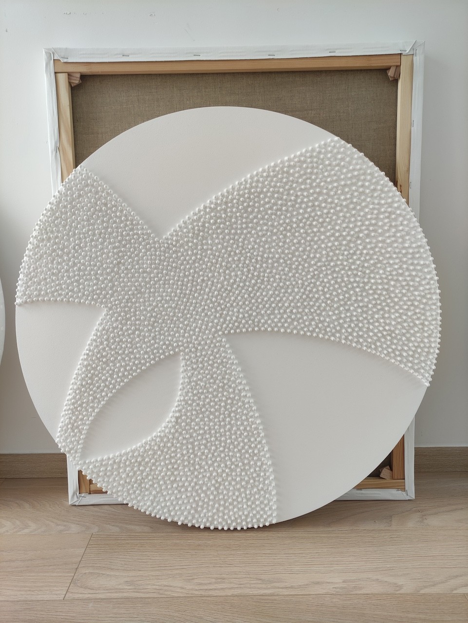 A large white sculpture on a wooden floor next to a white wall.