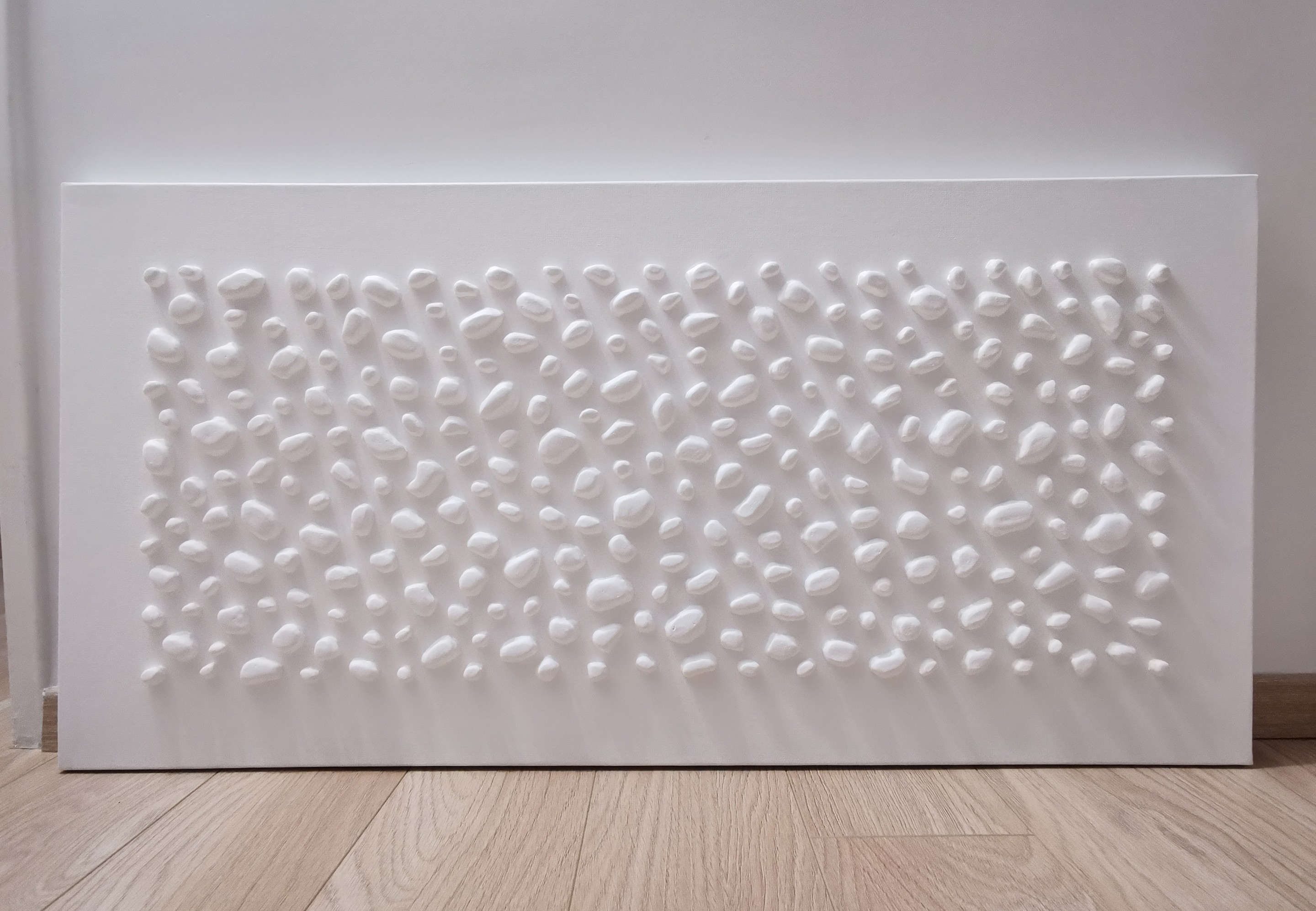 A white wall with a large white sculpture on it.