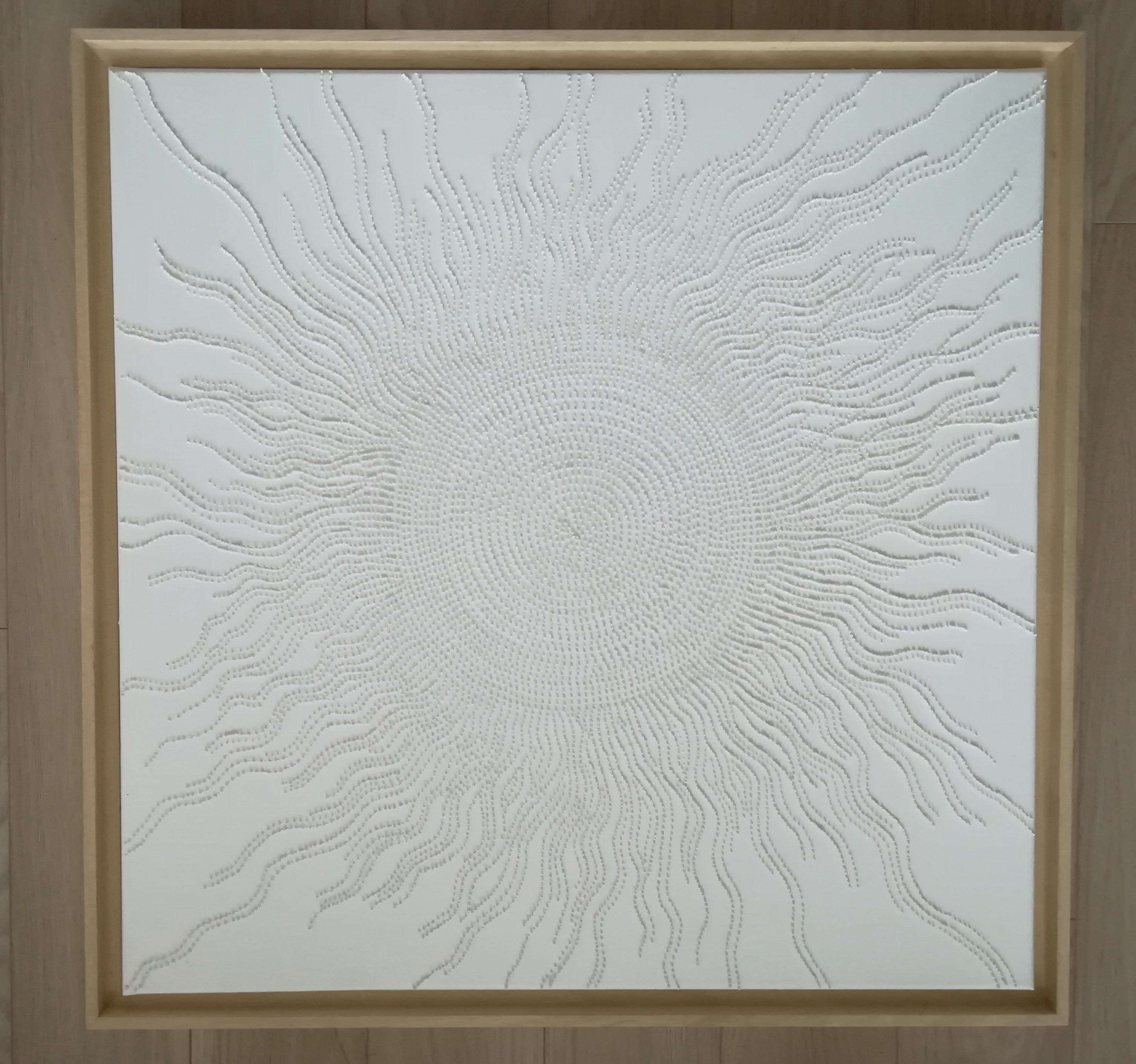 A large white painting on a white wall in a room.