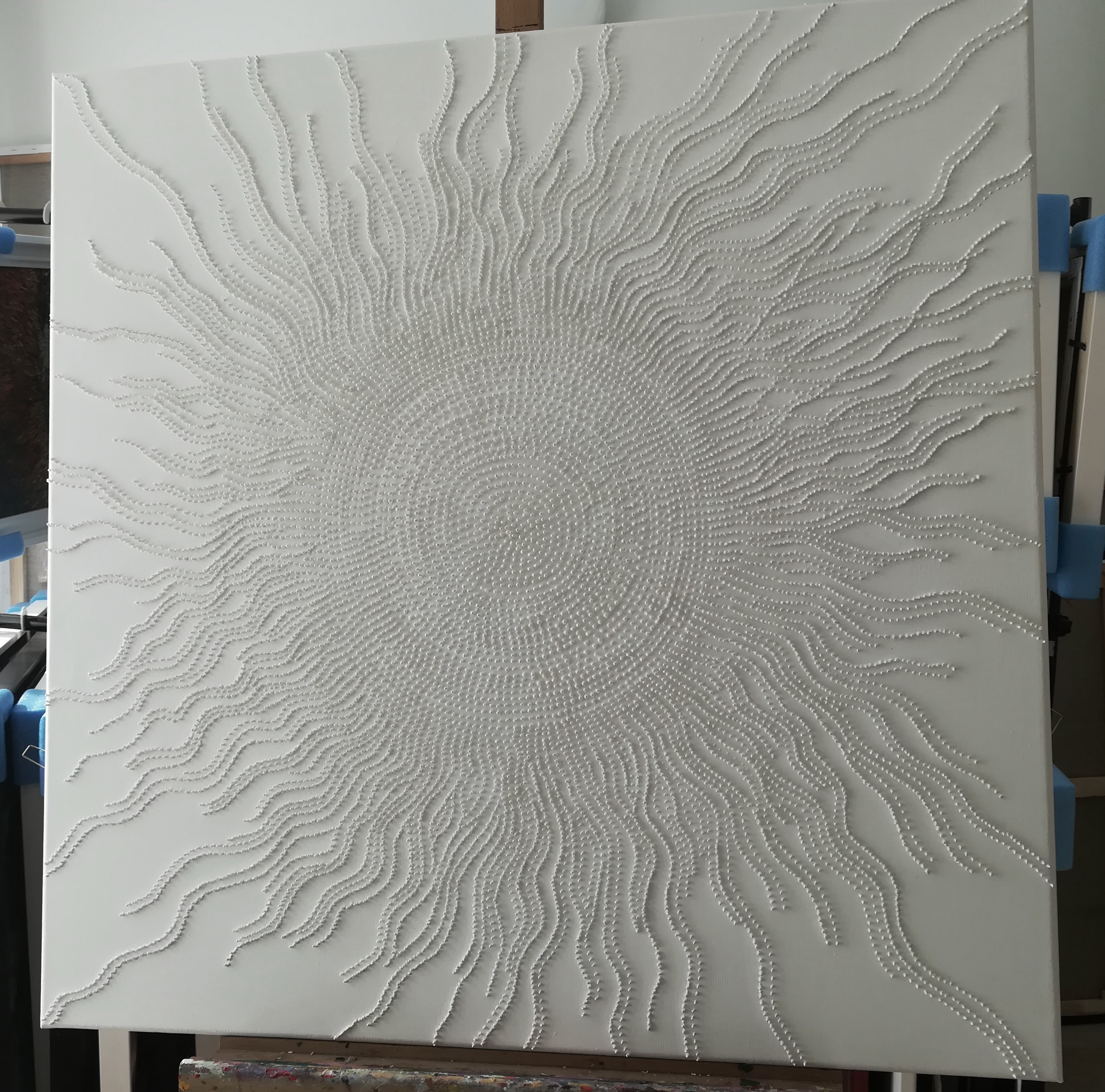 A large white painting on a white wall in a room.