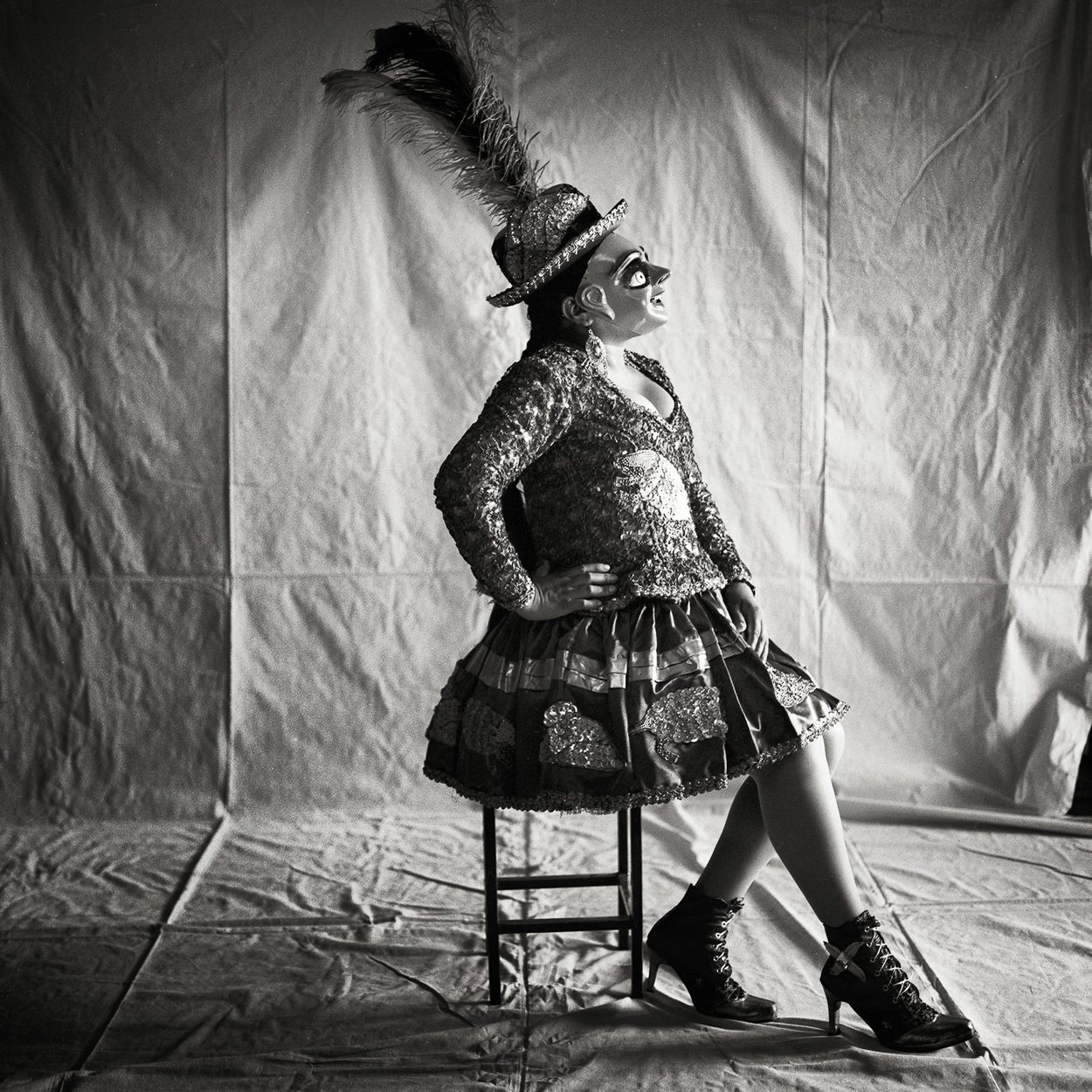 A woman in a costume sitting on a stool.