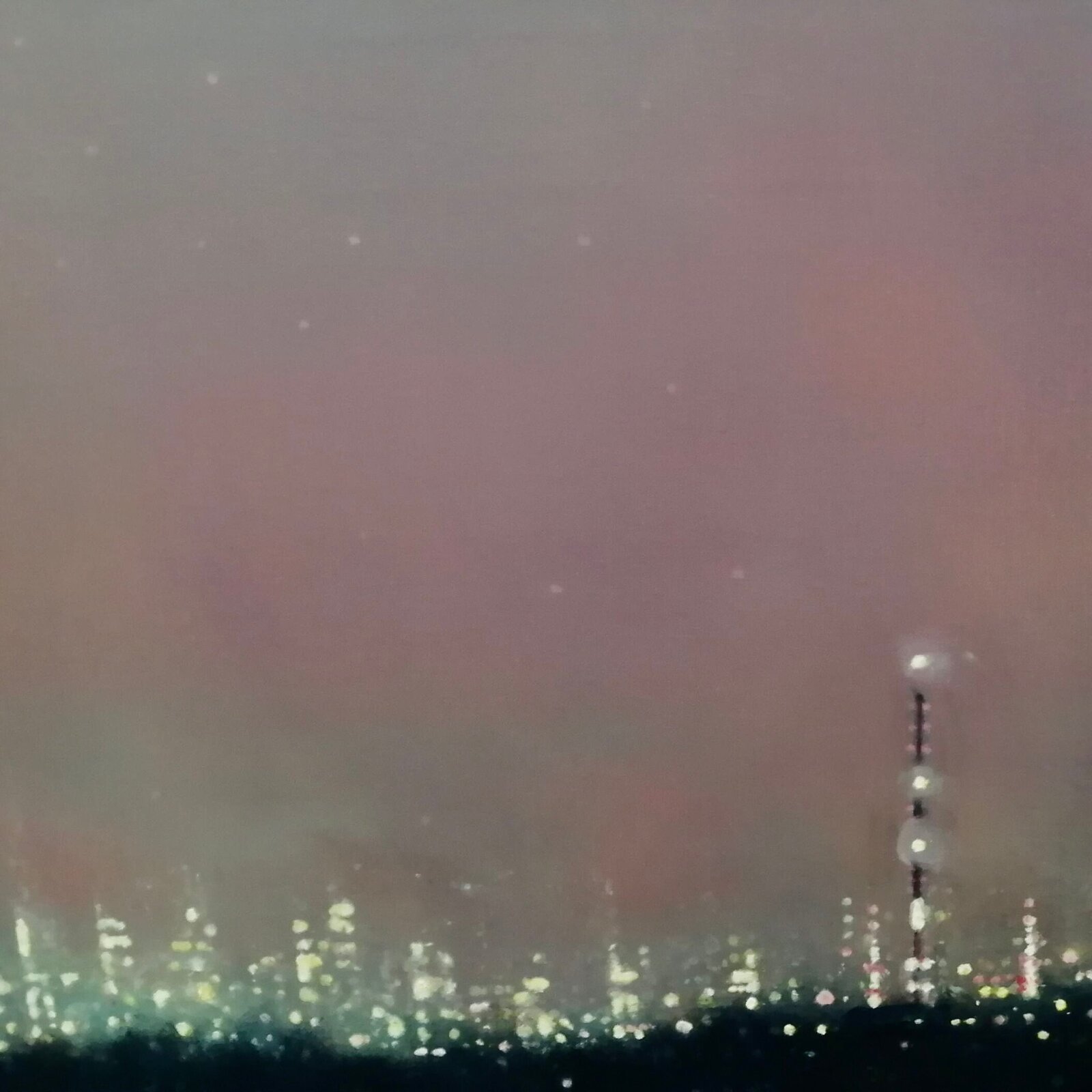 A moody night cityscape under a hazy, pink-hued sky with a bright celestial body.