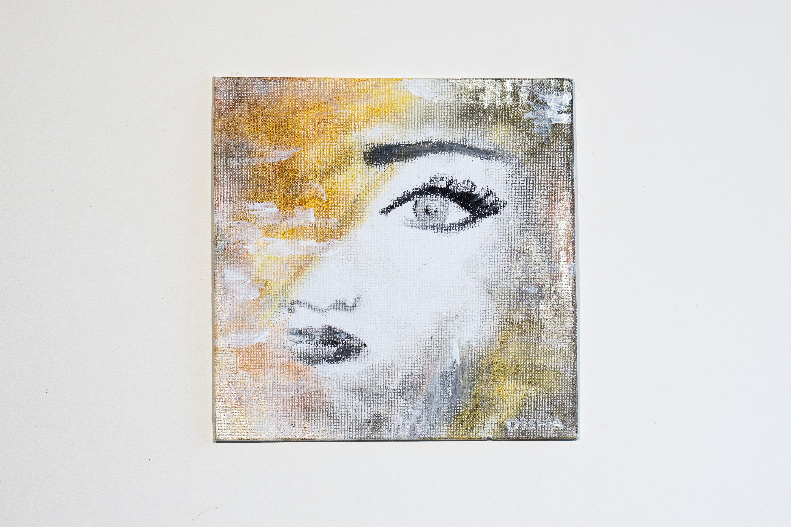 A painting of a woman's face on a white wall.