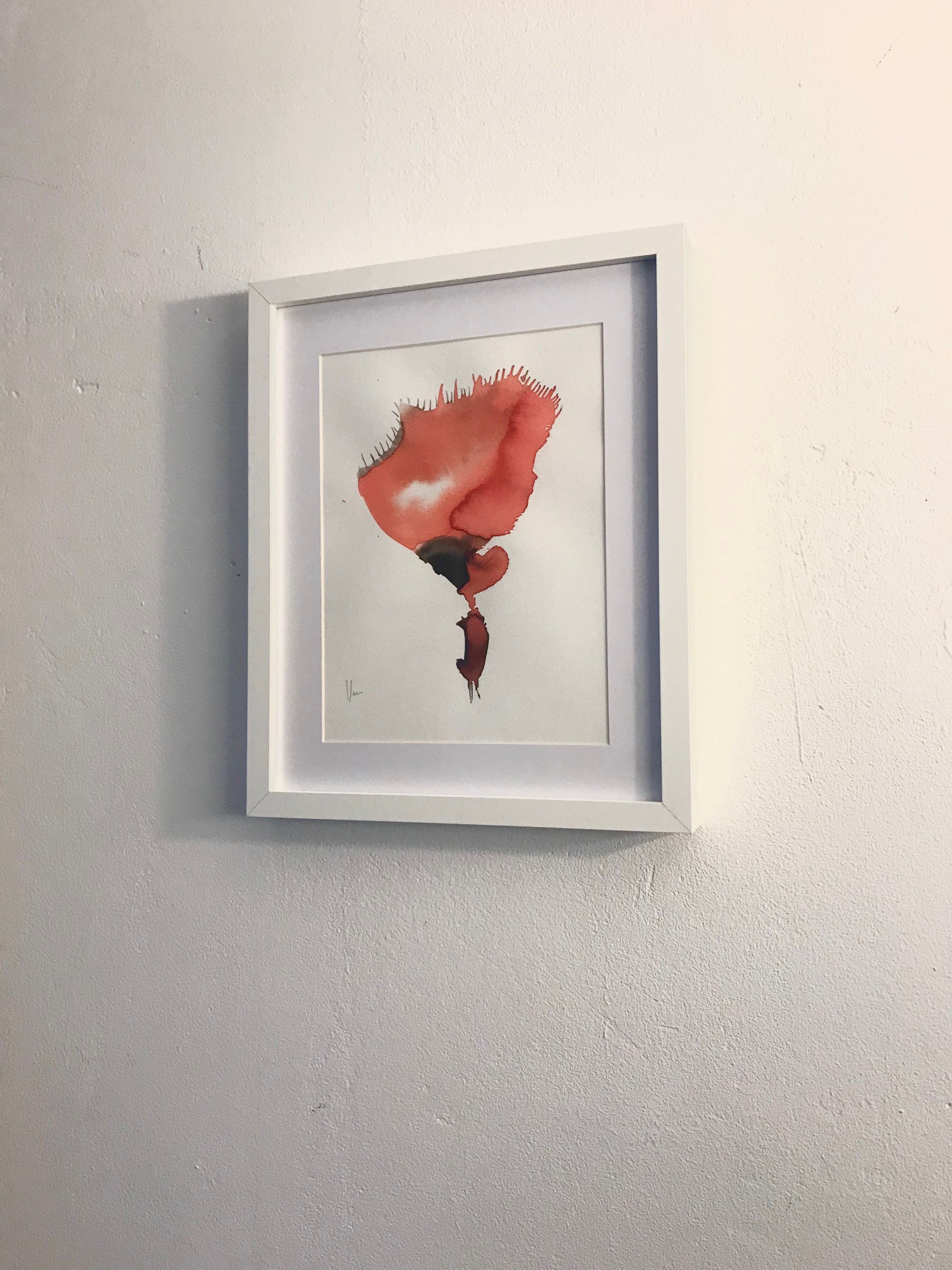 A watercolor painting of a red flower in a white frame.
