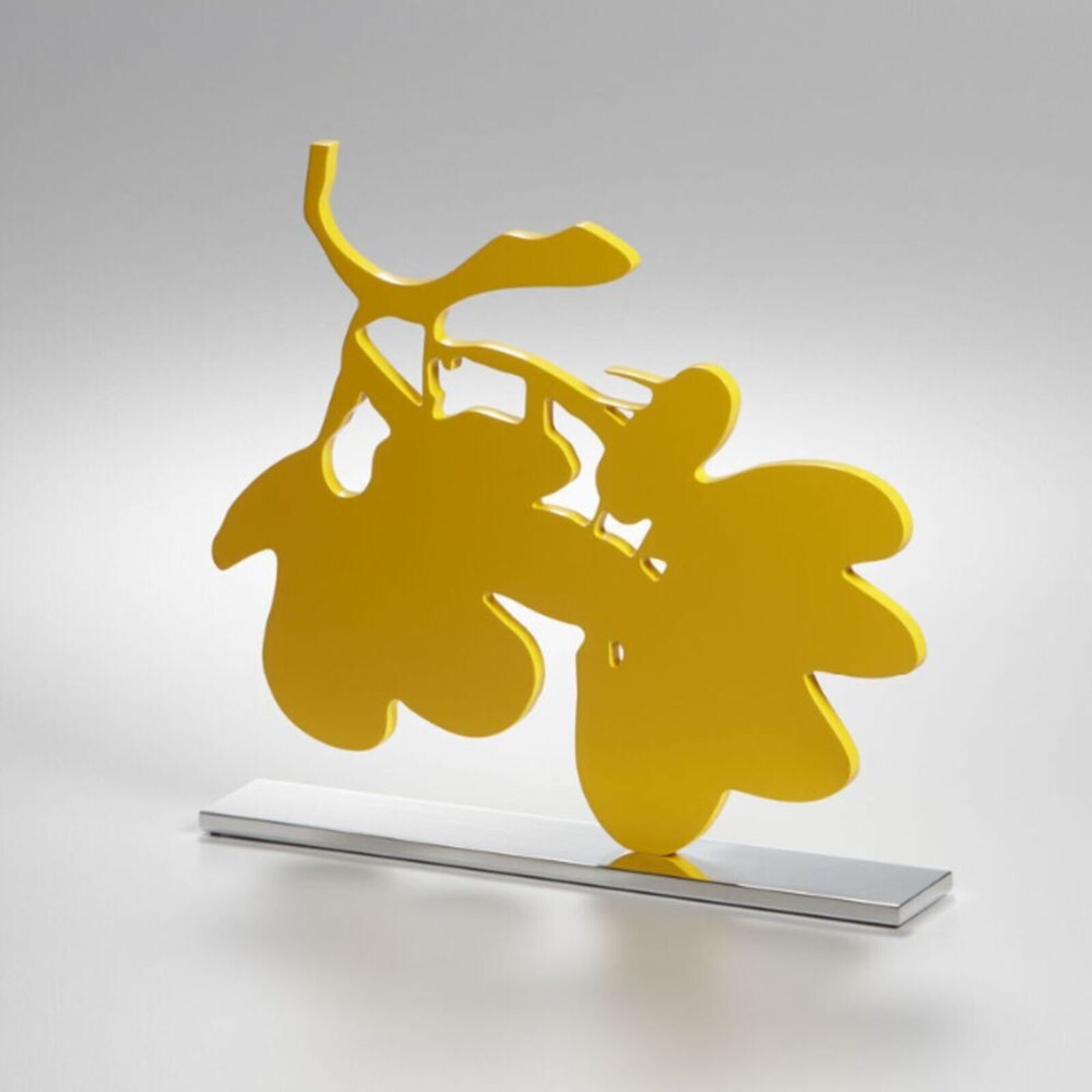A yellow sculpture of a bunch of grapes on a metal stand.