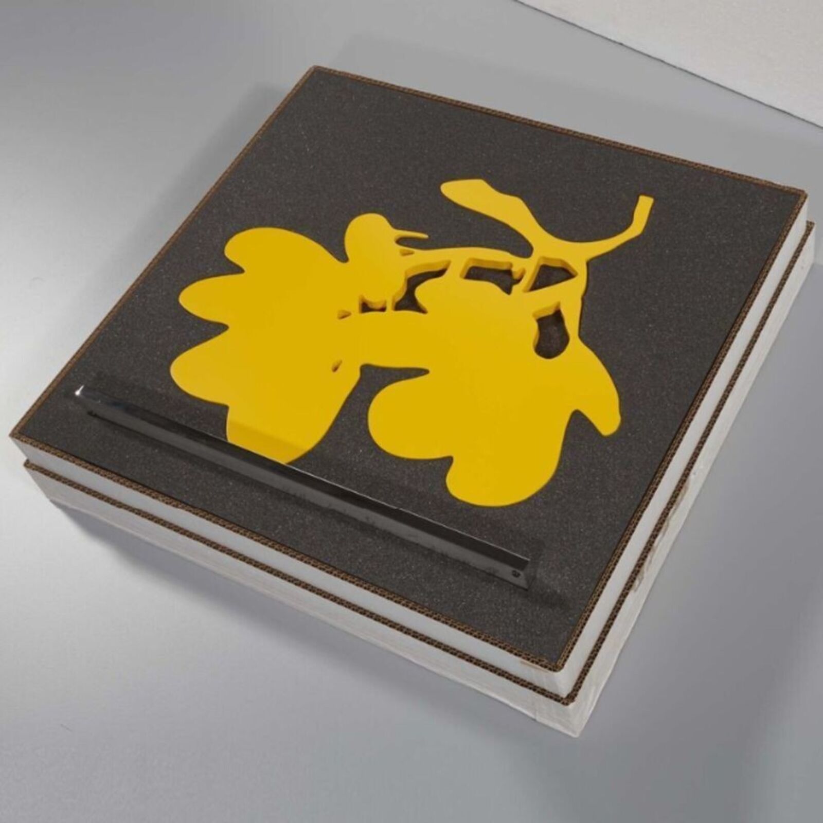 A yellow sculpture of a bunch of grapes on a metal stand.