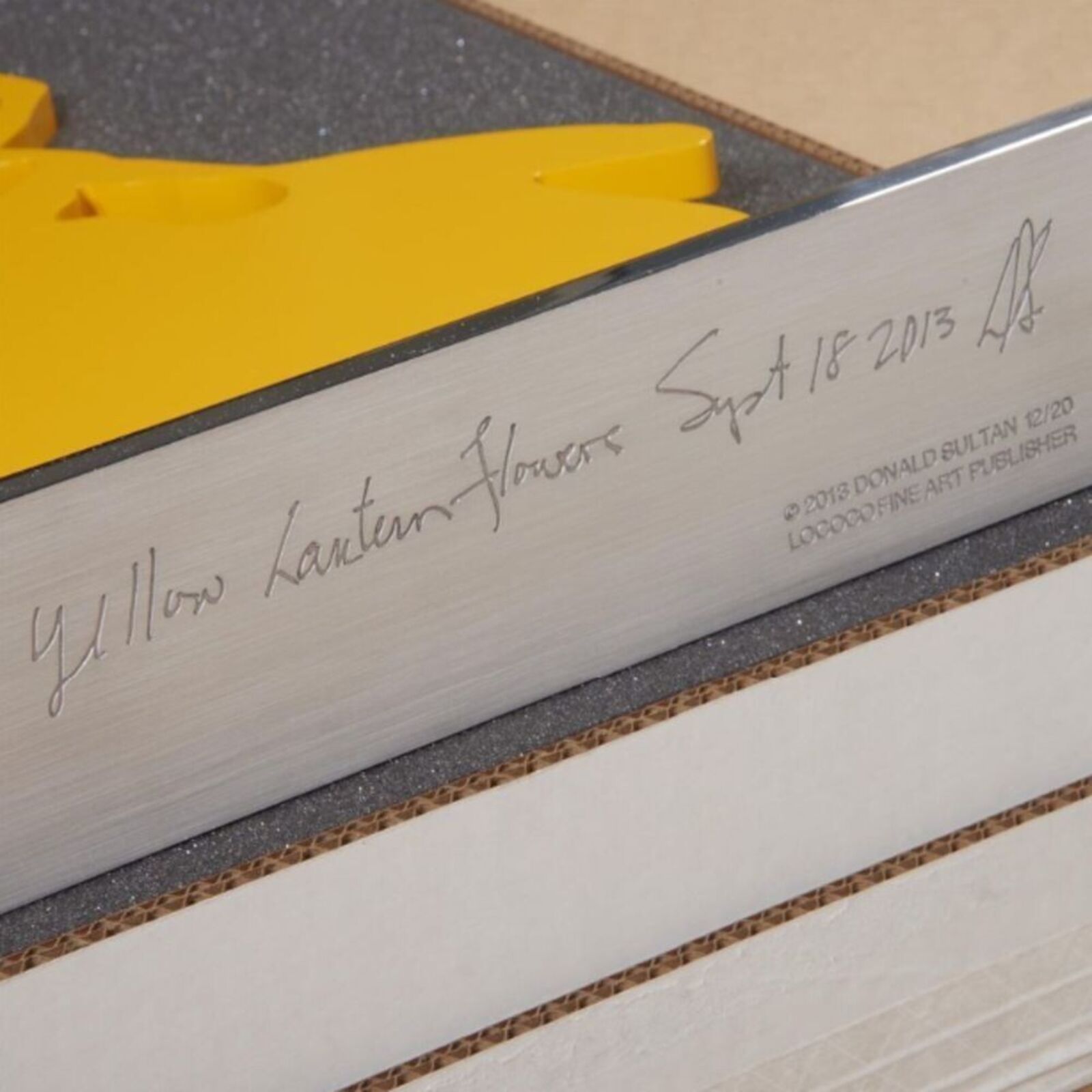 A yellow sculpture of a bunch of grapes on a metal stand.