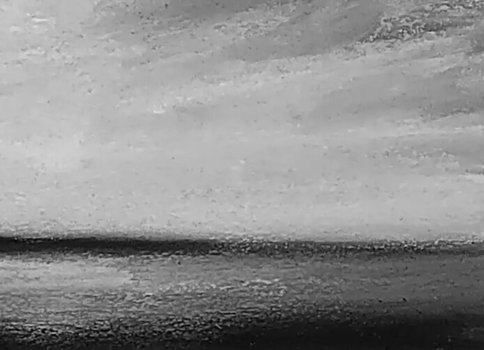 A moody monochrome seascape featuring a turbulent sky over a dark horizon.
