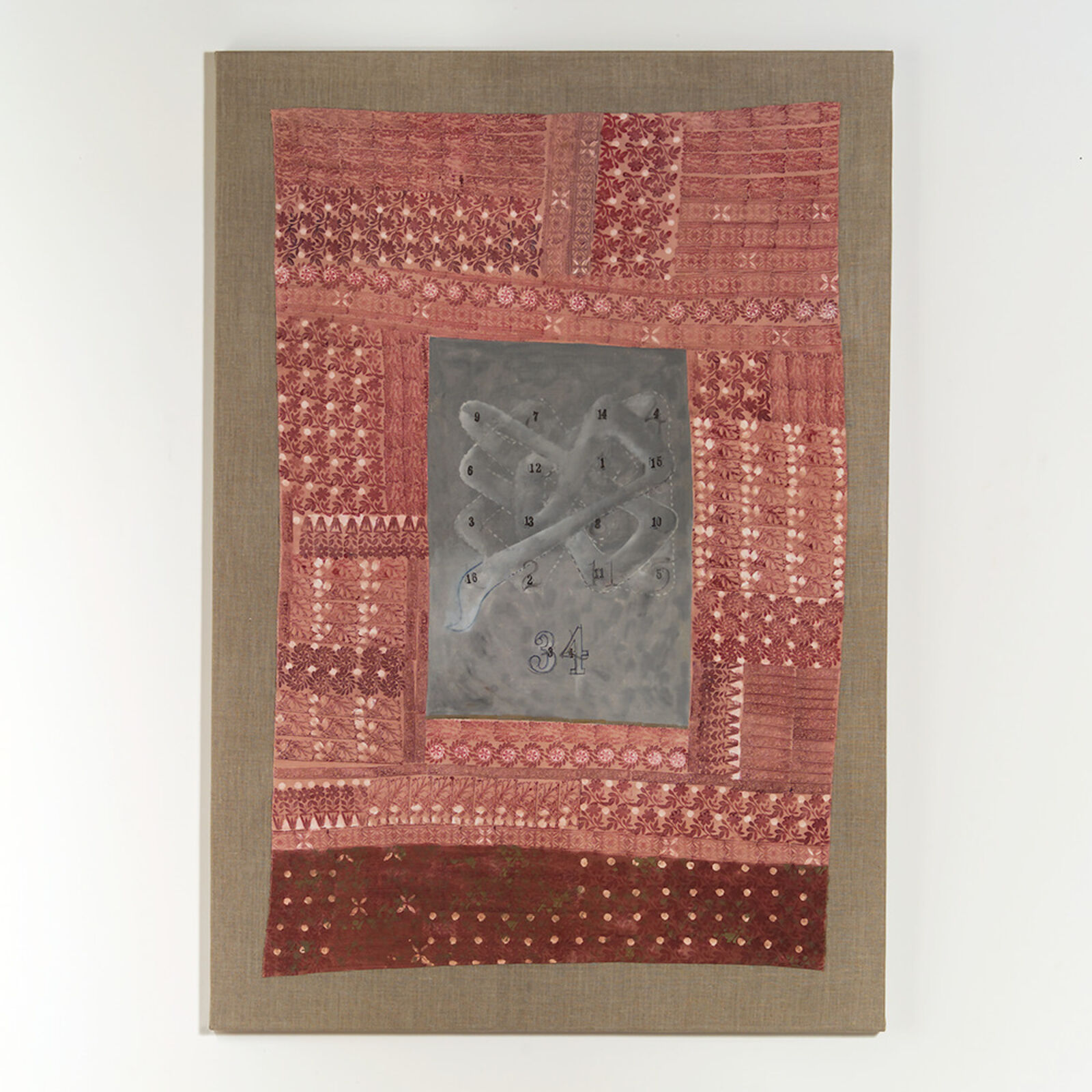 A textile artwork featuring a patchwork background with a central metallic panel displaying abstract geometric forms.
