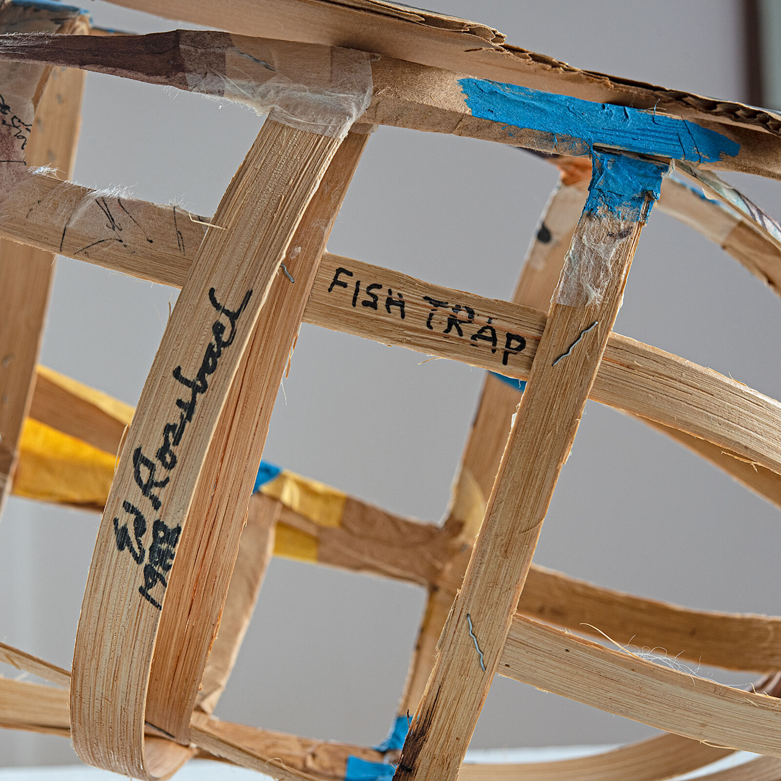 "A whimsical sculpture of a fish-shaped basket with blue and natural wood tones."