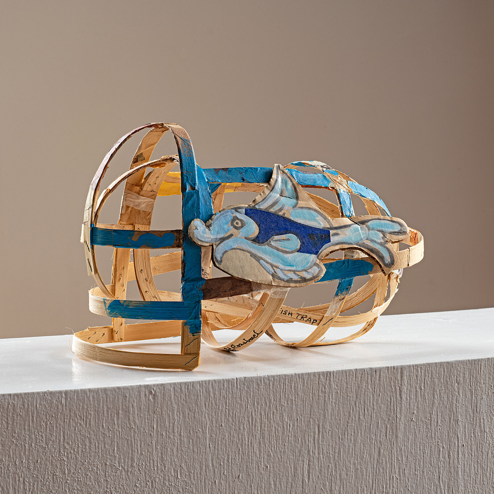 "A whimsical sculpture of a fish-shaped basket with blue and natural wood tones."
