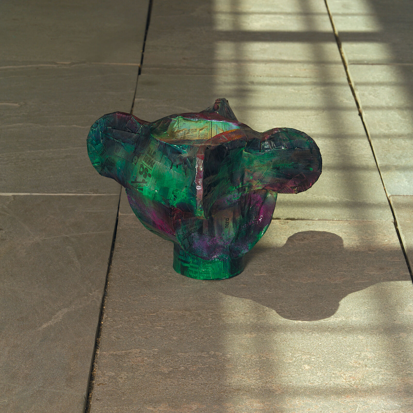 A green vase sitting on a sidewalk next to a sidewalk.