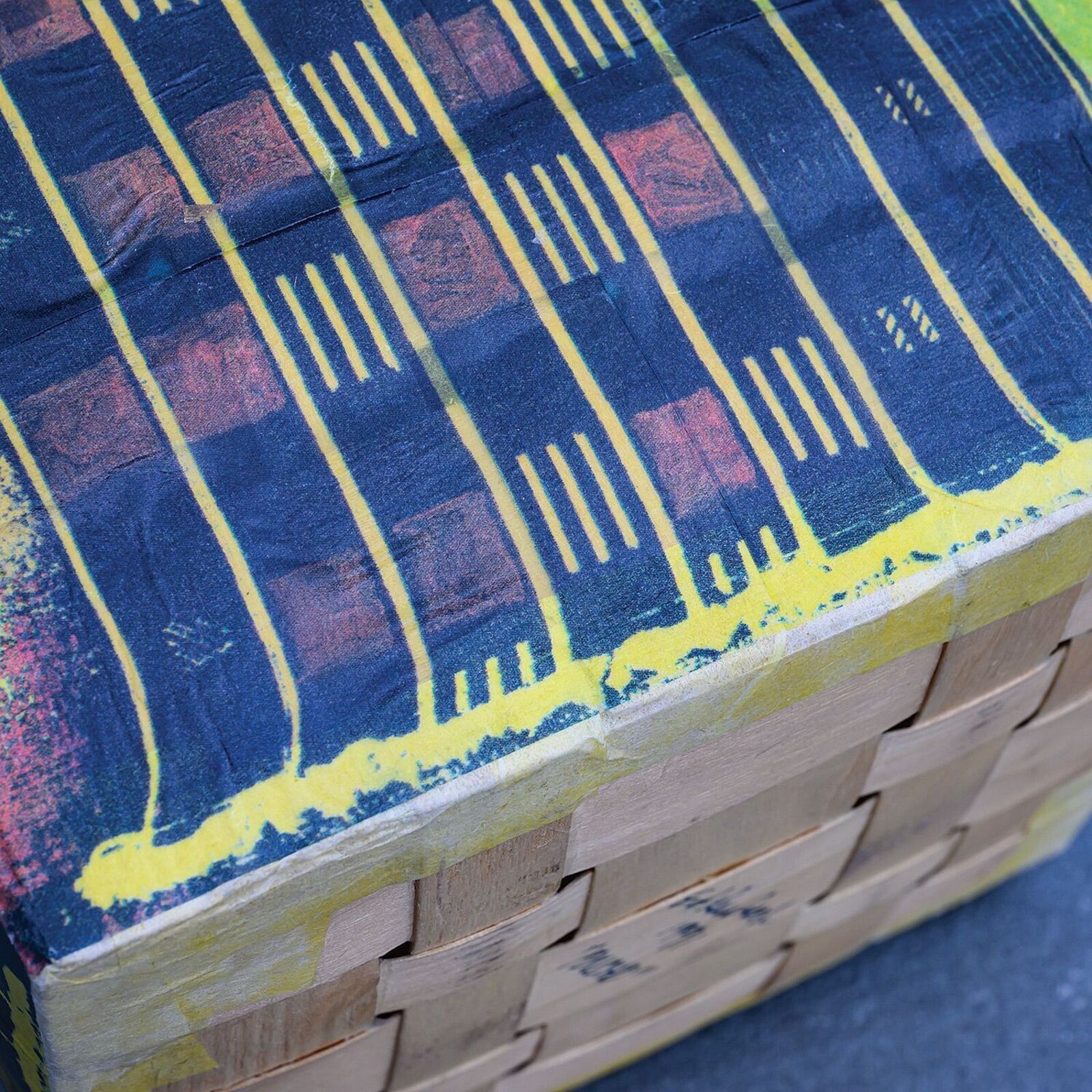 A colorful, cube-shaped box with a geometric pattern and a square opening on top.