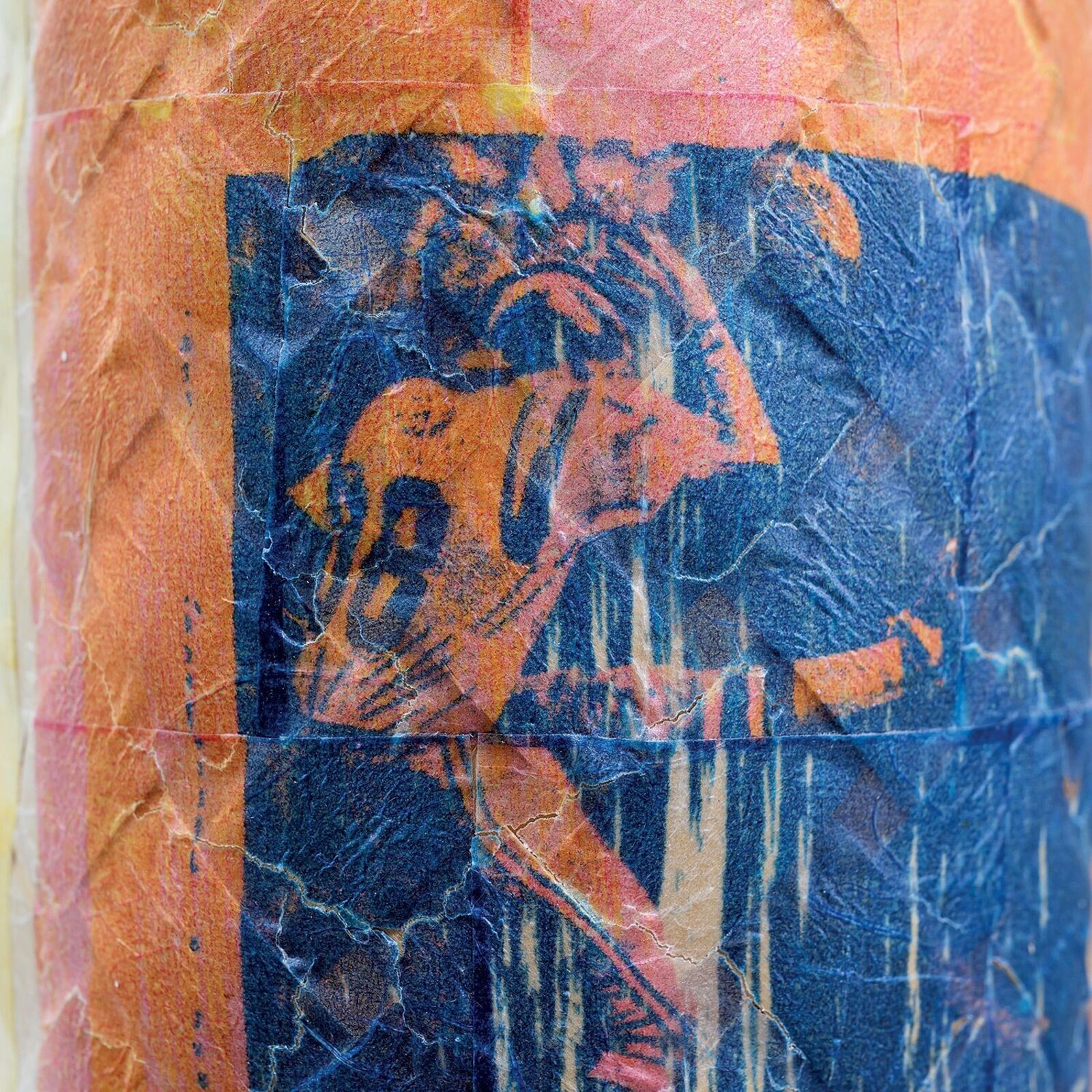 A textured, multi-colored vase featuring a blue square print of a figure.