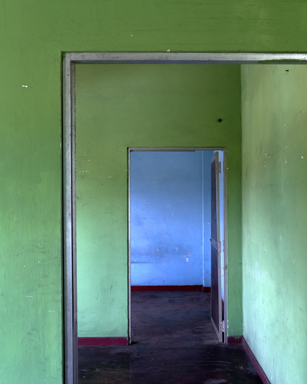An open door in an empty room with green walls.
