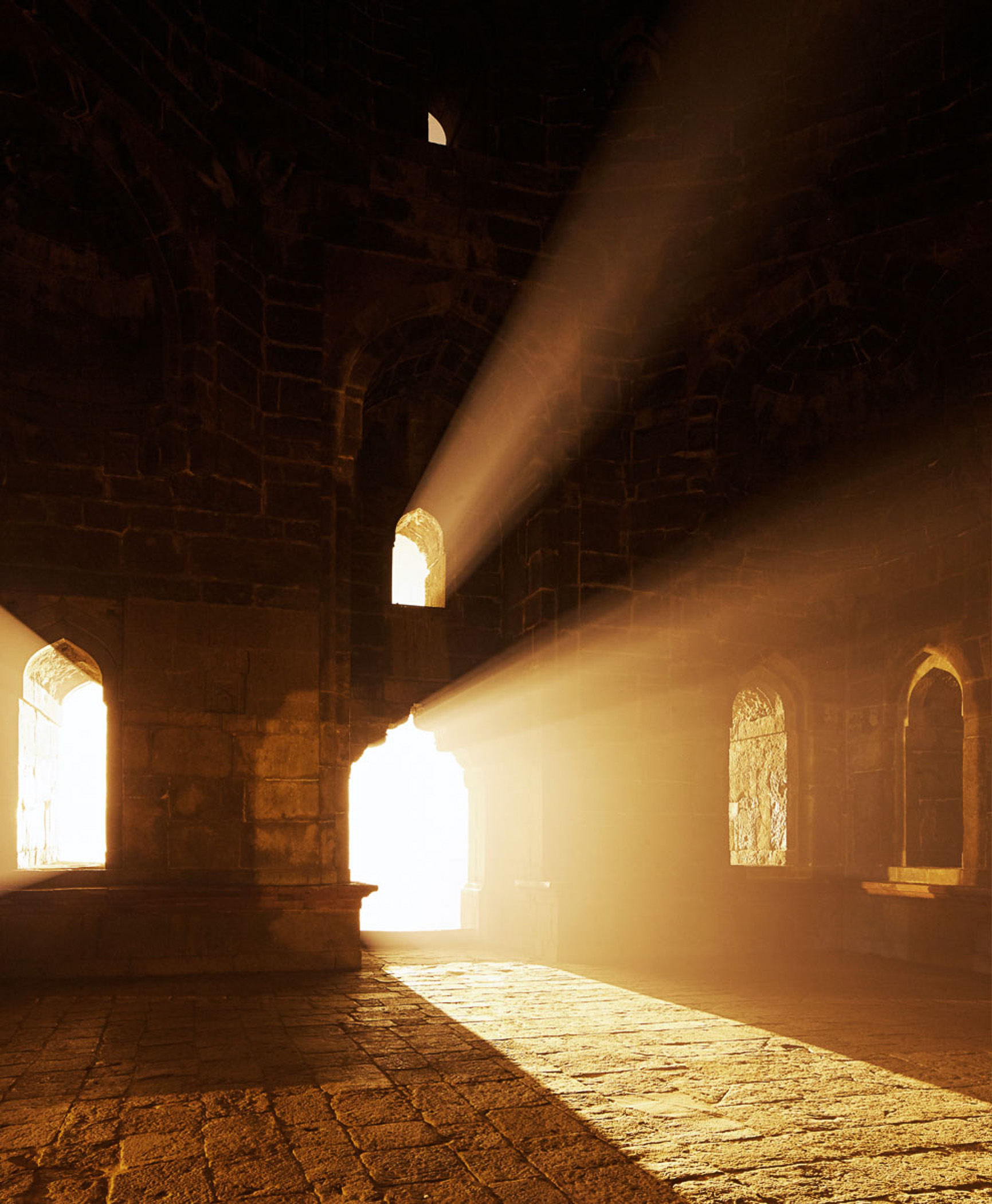The sun is shining through the arches of an old building.