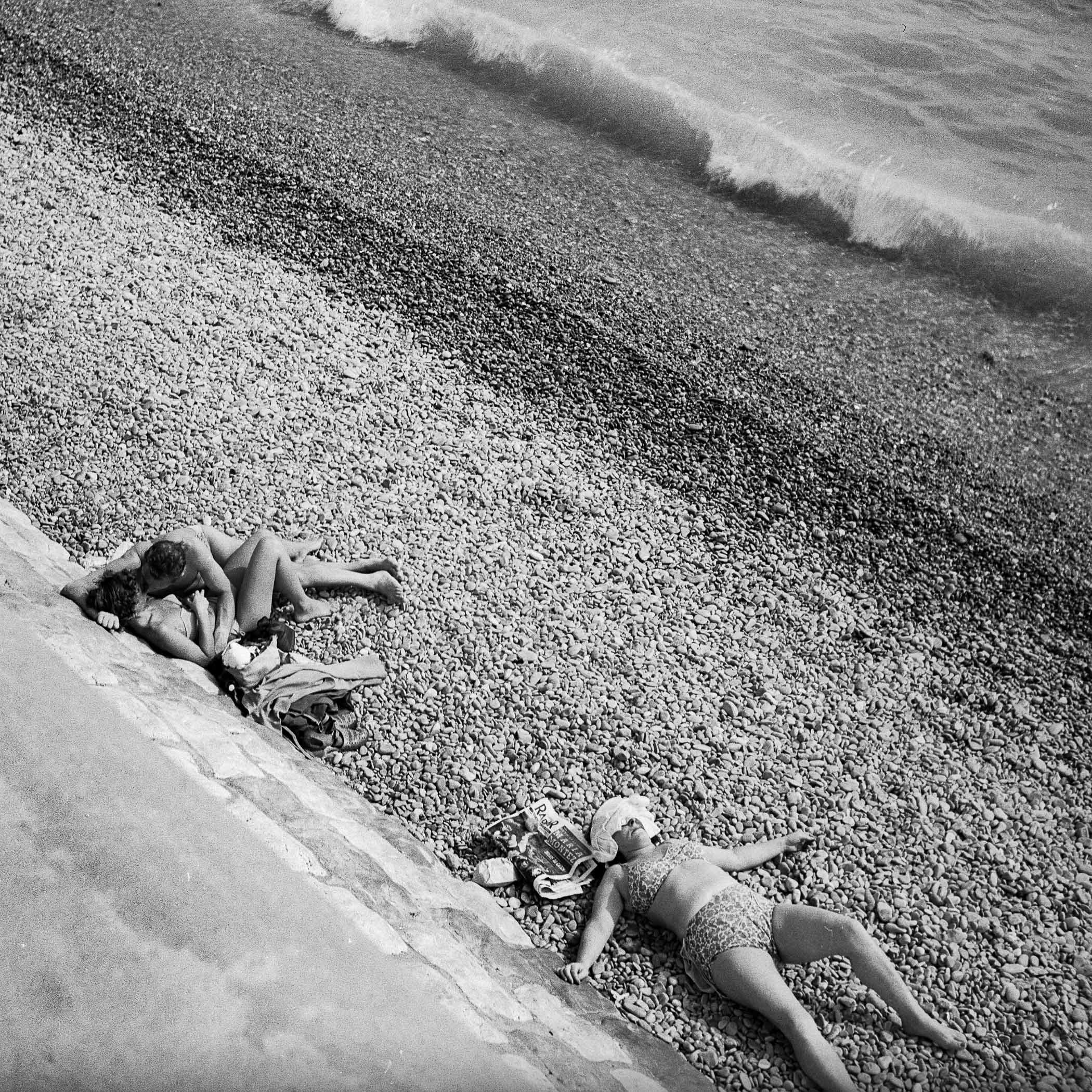 A couple of people laying on top of a beach next to the ocean.