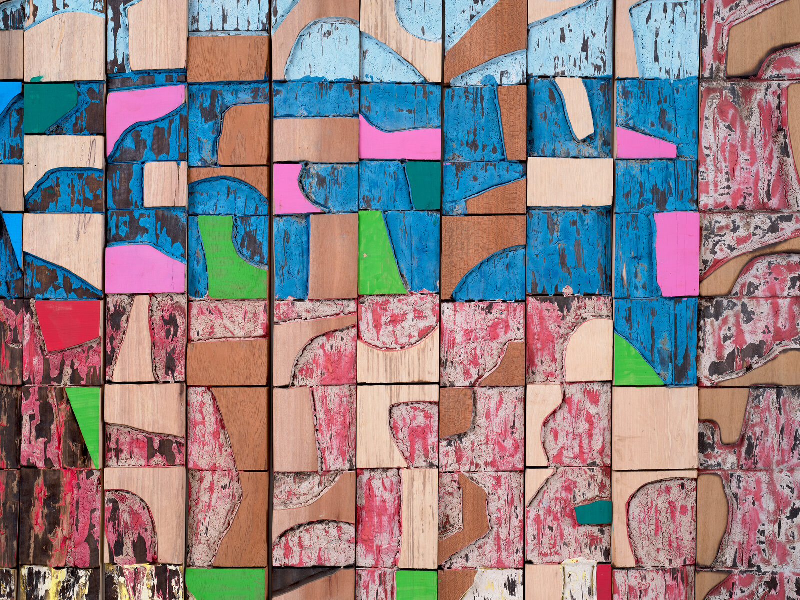A colorful, abstract wooden wall sculpture composed of many small painted blocks.