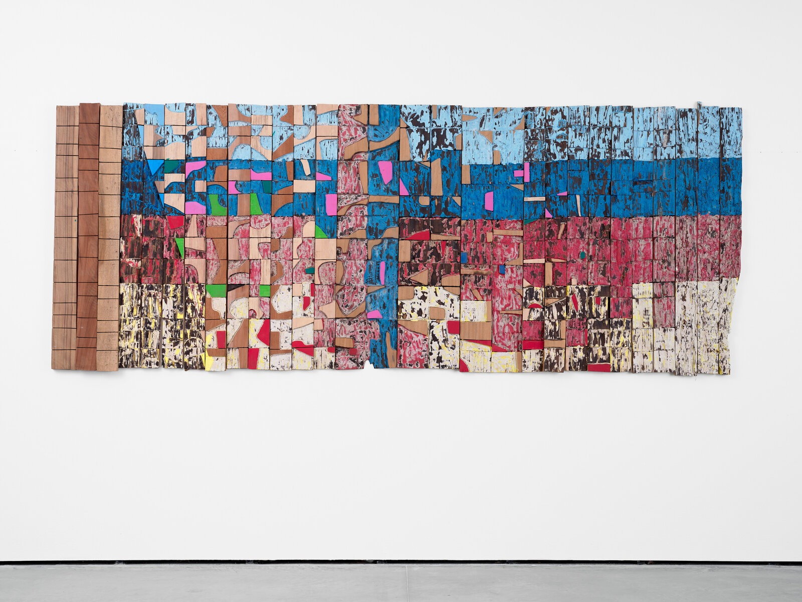 A colorful, abstract wooden wall sculpture composed of many small painted blocks.