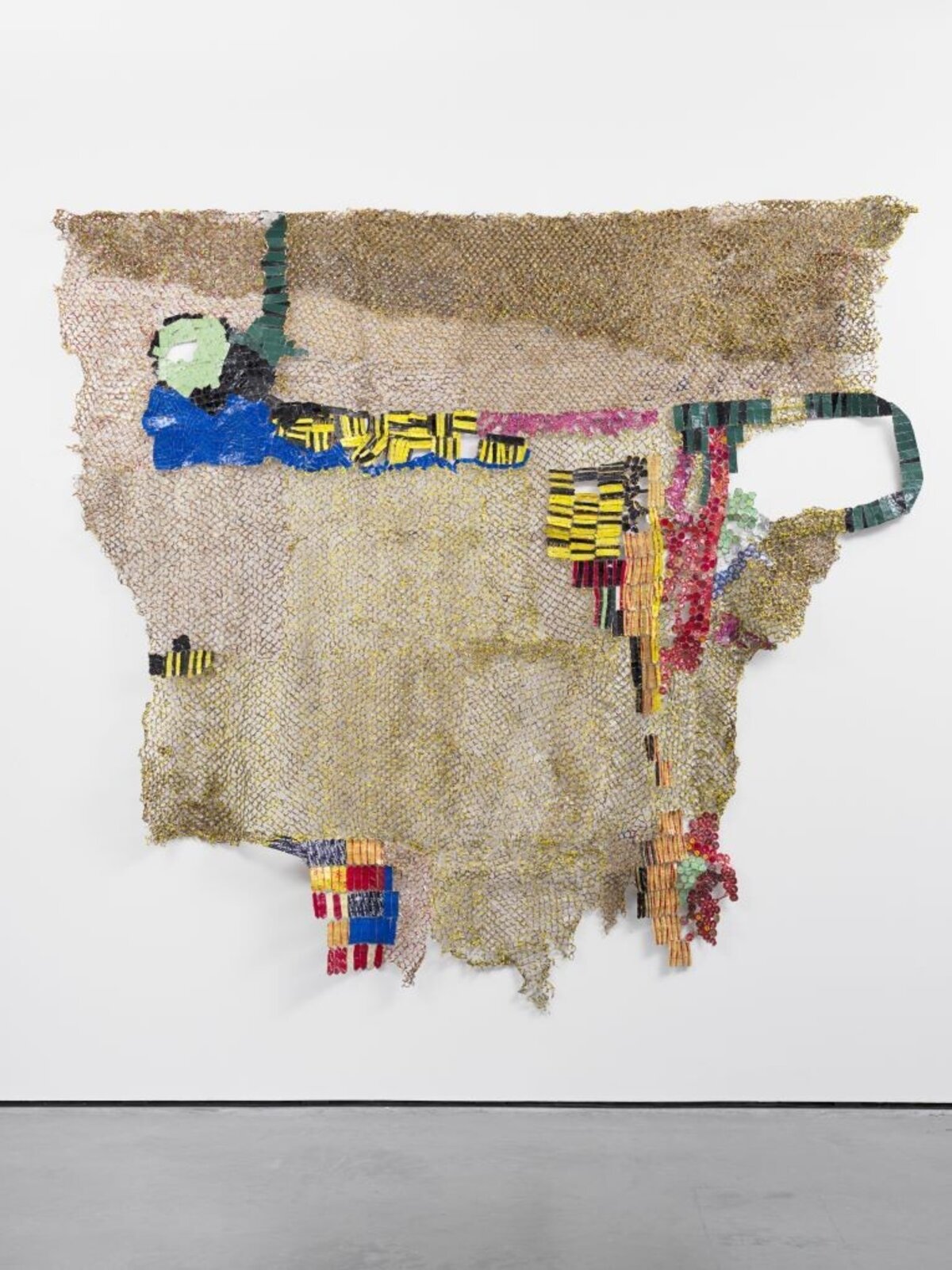 A textured, net-like sculpture featuring a stylized figure and colorful geometric elements against a plain white wall.
