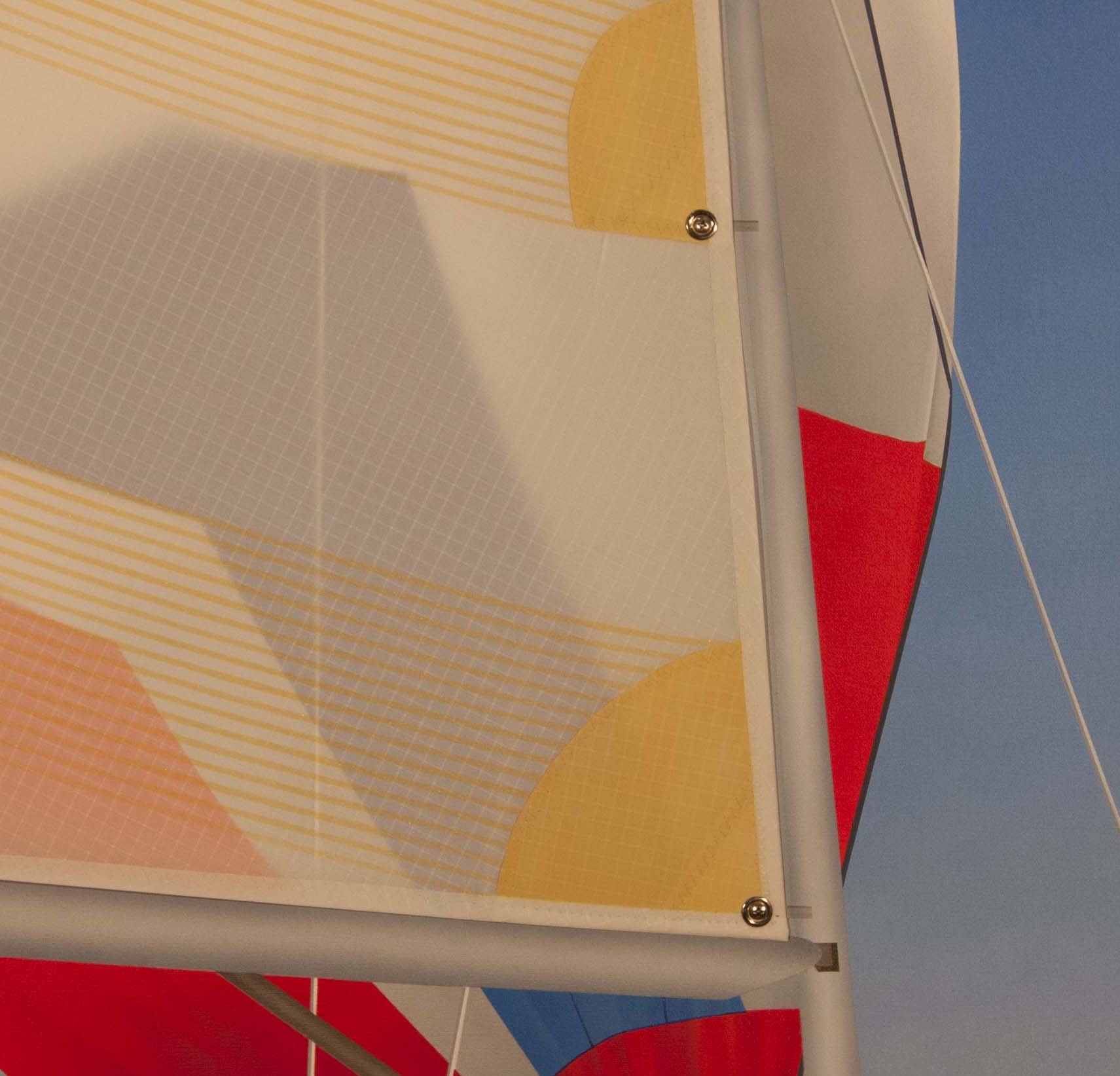 A close up of a sail on a sailboat against a blue sky.