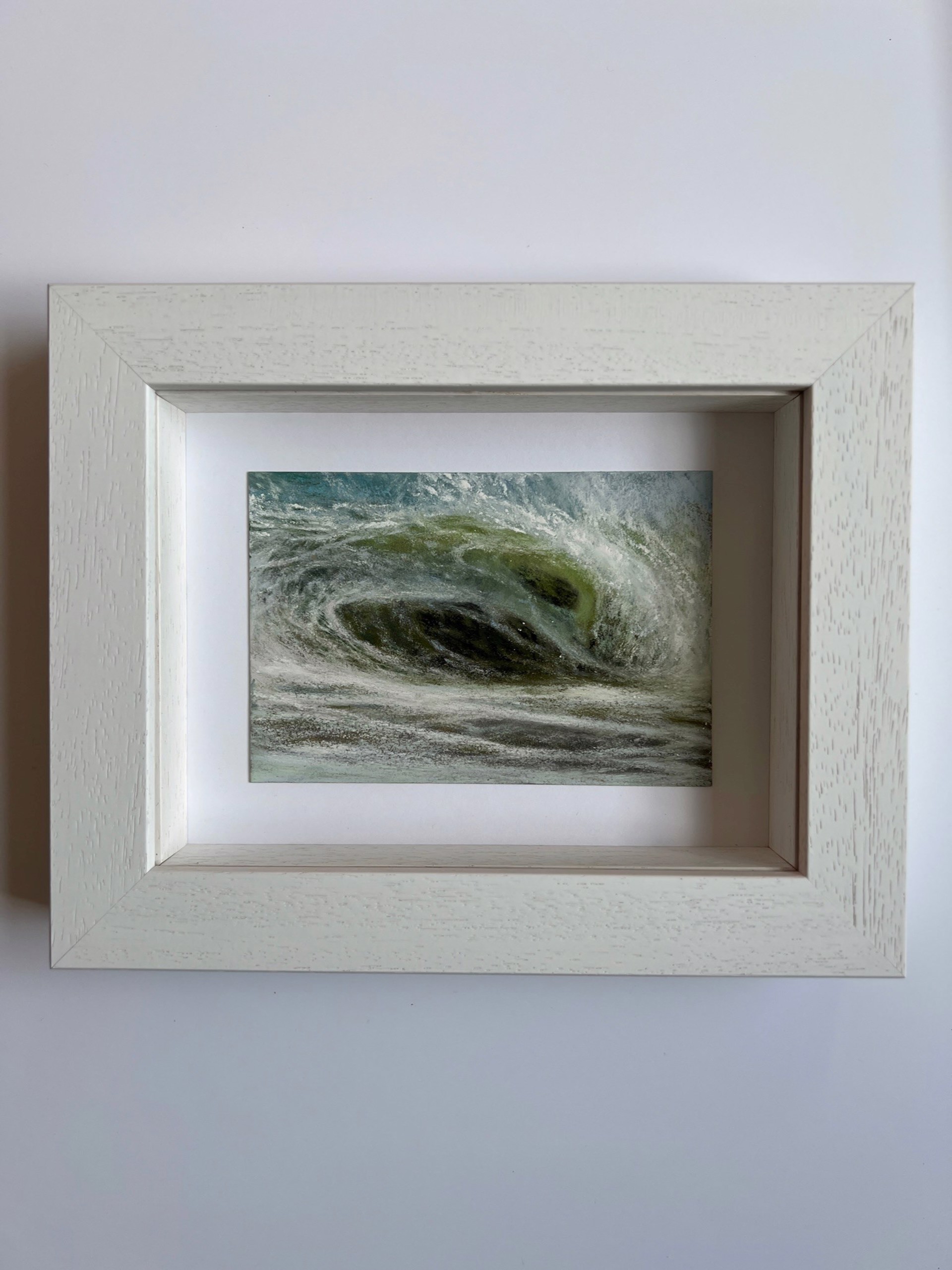 A large wave crashes against the shore of a beach.