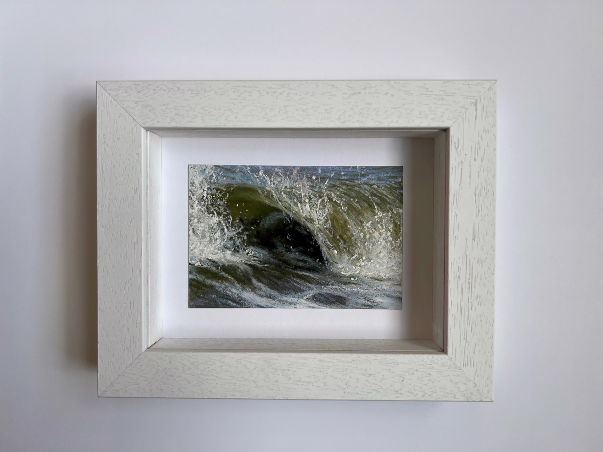 A close up of a large wave breaking over a rock in the water.