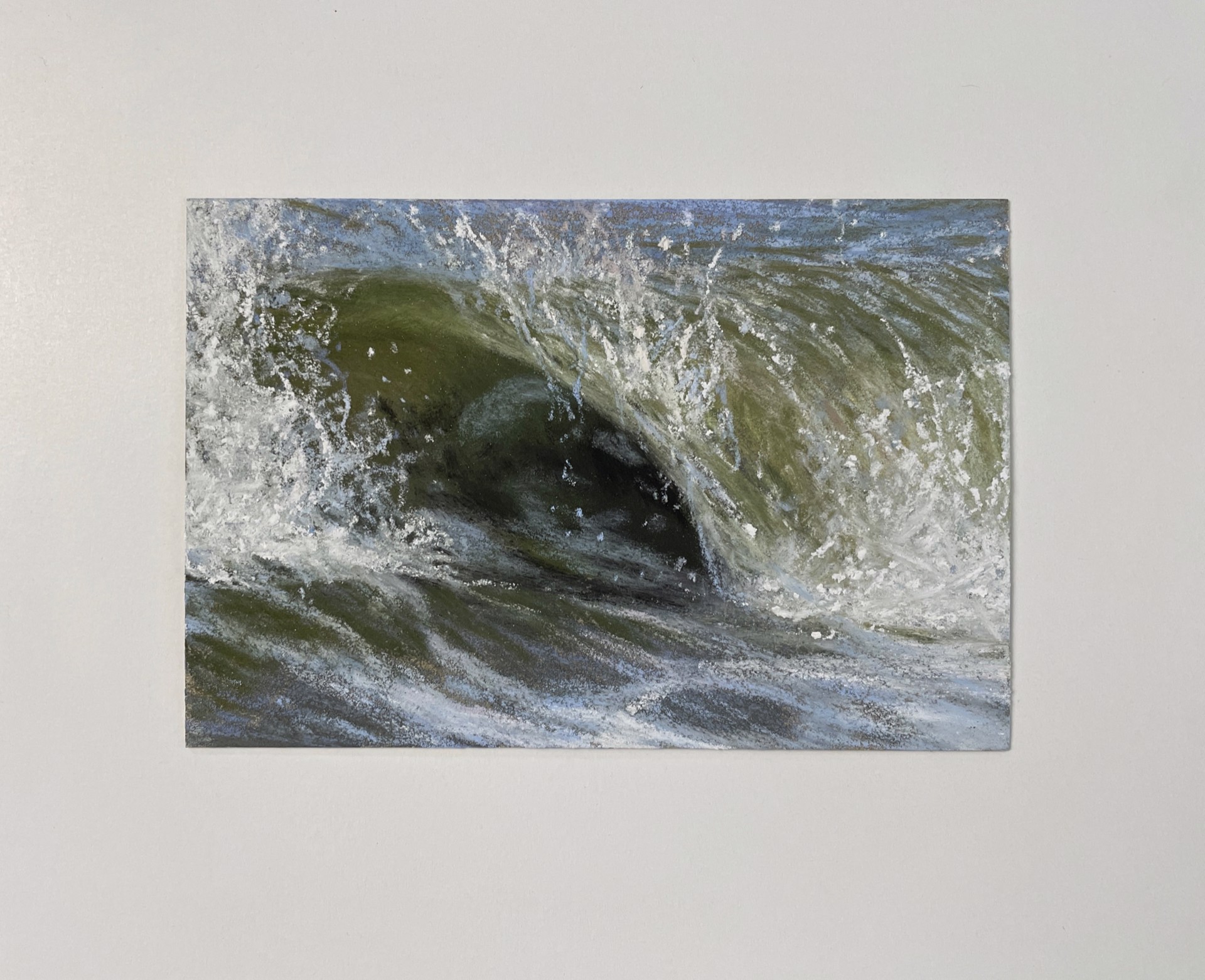 A close up of a large wave breaking over a rock in the water.