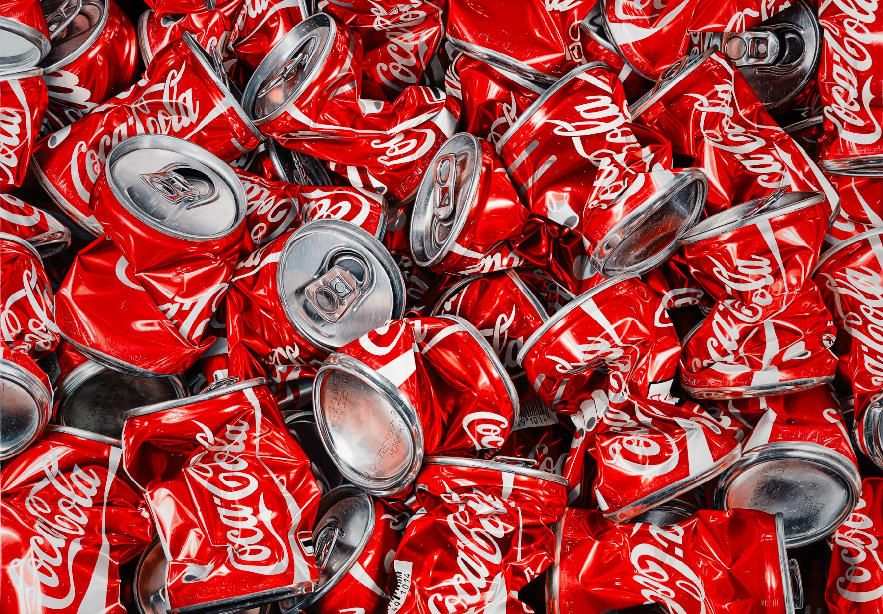 A pile of coca cola cans sitting on top of each other.