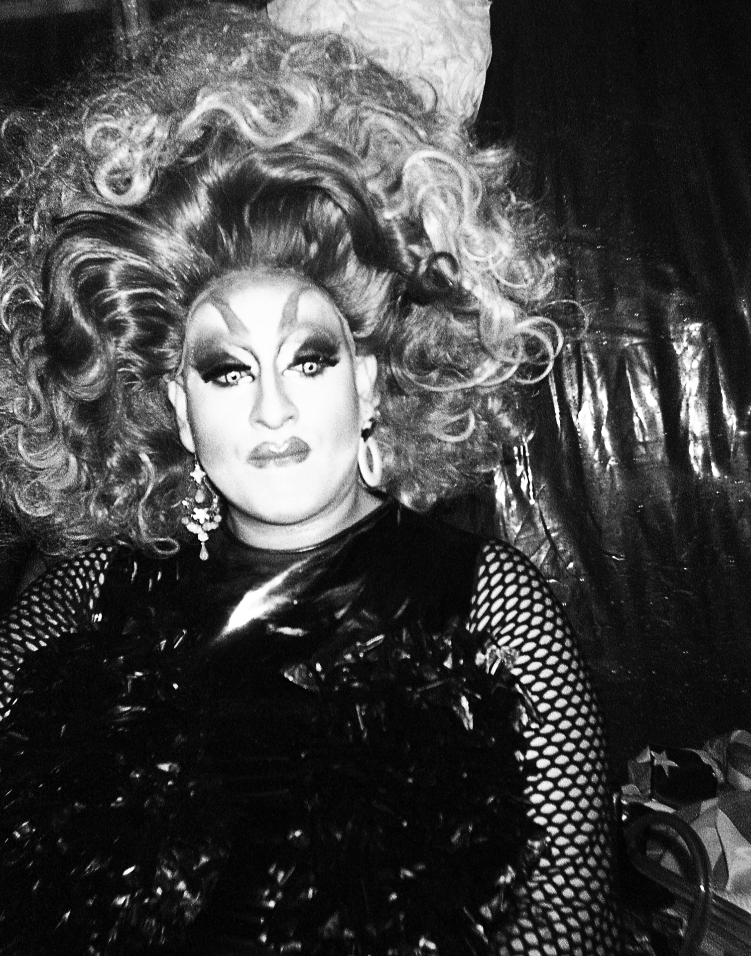 A black and white photo of a woman in a drag queen costume.