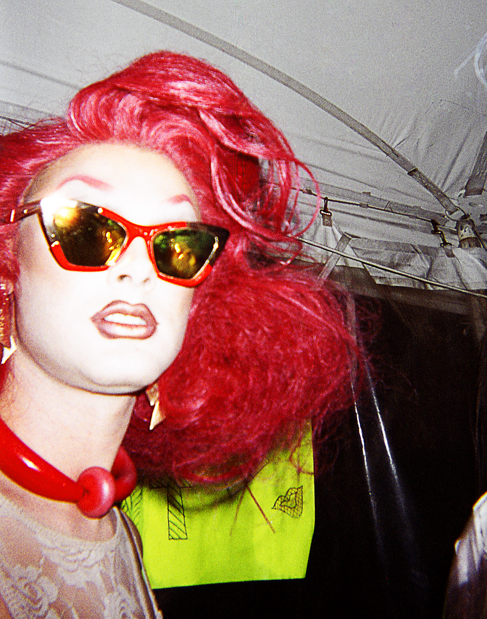 A mannequin wearing a red wig and sunglasses. 